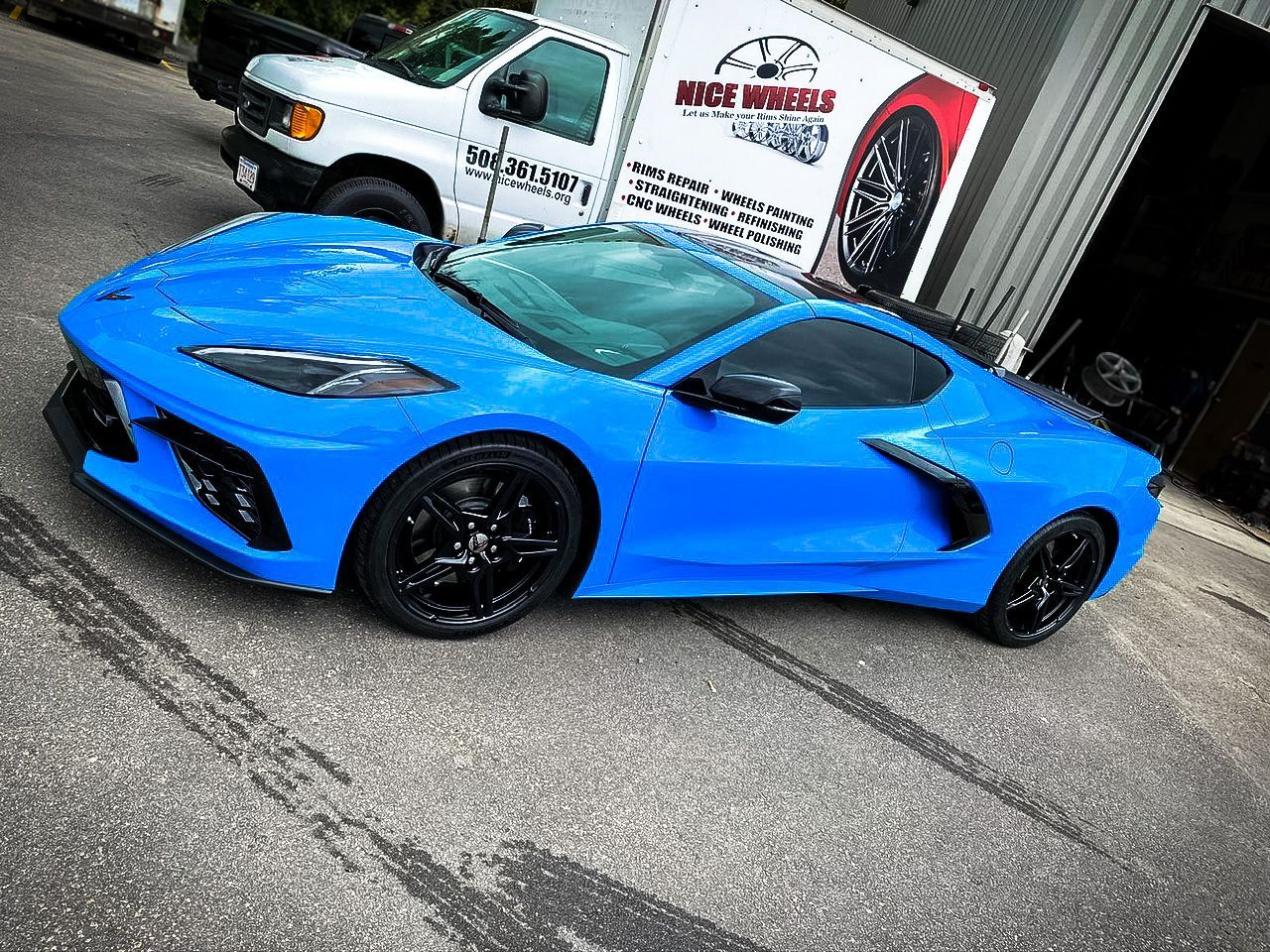 A blue sports car is parked in front of a white truck.