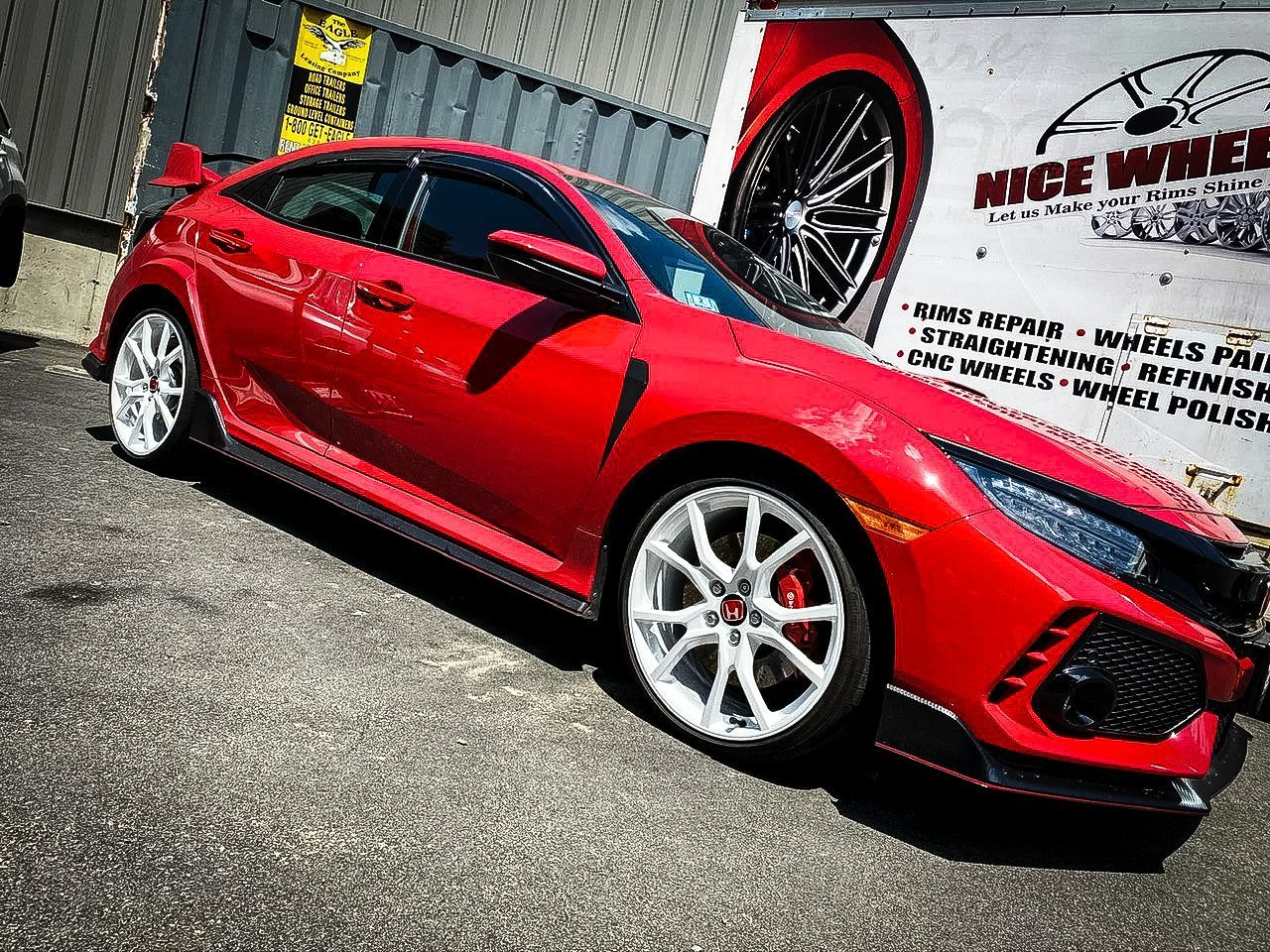 A red honda civic type r is parked in front of a wheel shop.