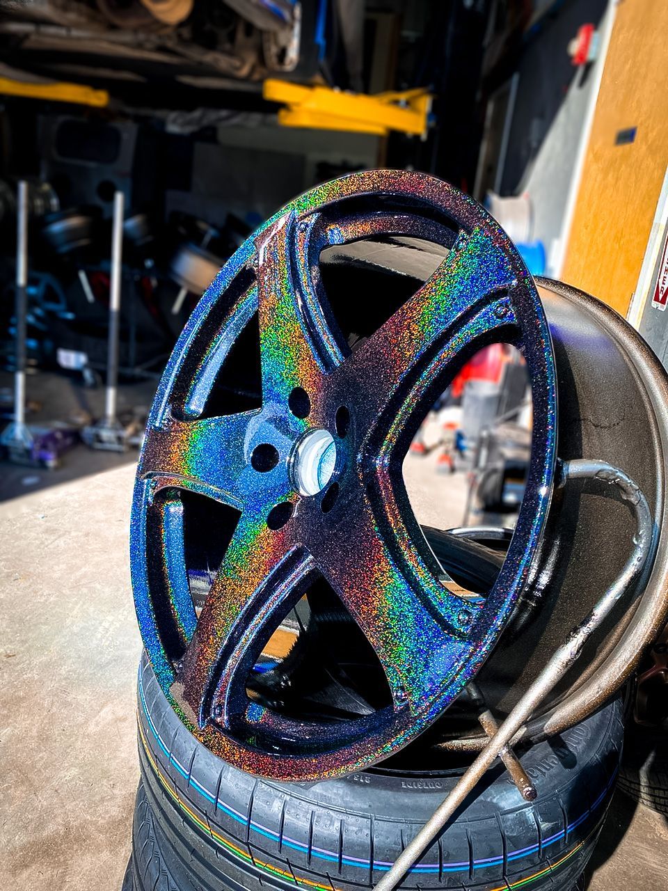 A wheel is sitting on top of a tire in a garage.
