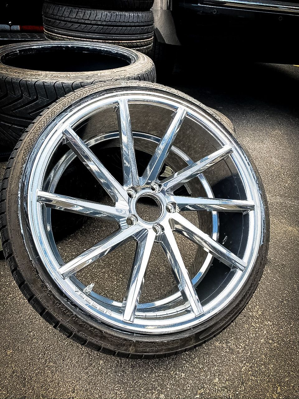 A close up of a chrome wheel and tire on the ground.