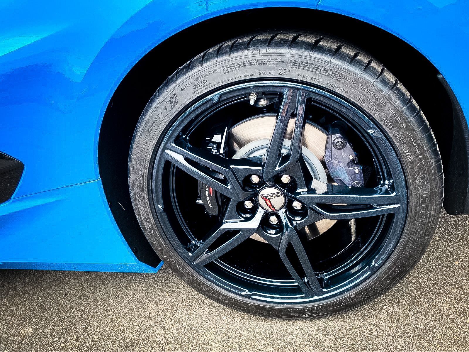 A close up of a blue sports car wheel with a black tire.