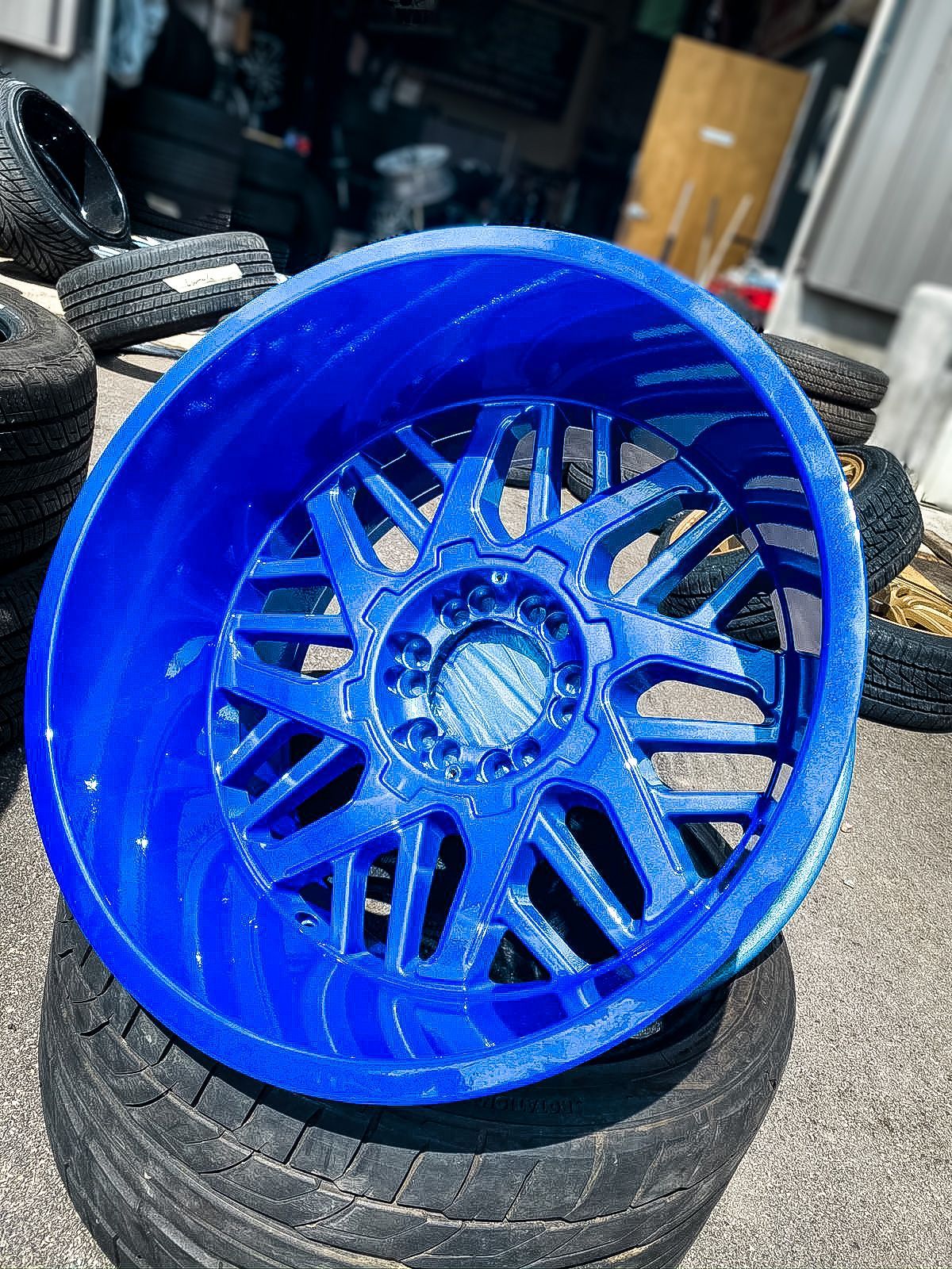 A blue wheel is sitting on top of a pile of tires.