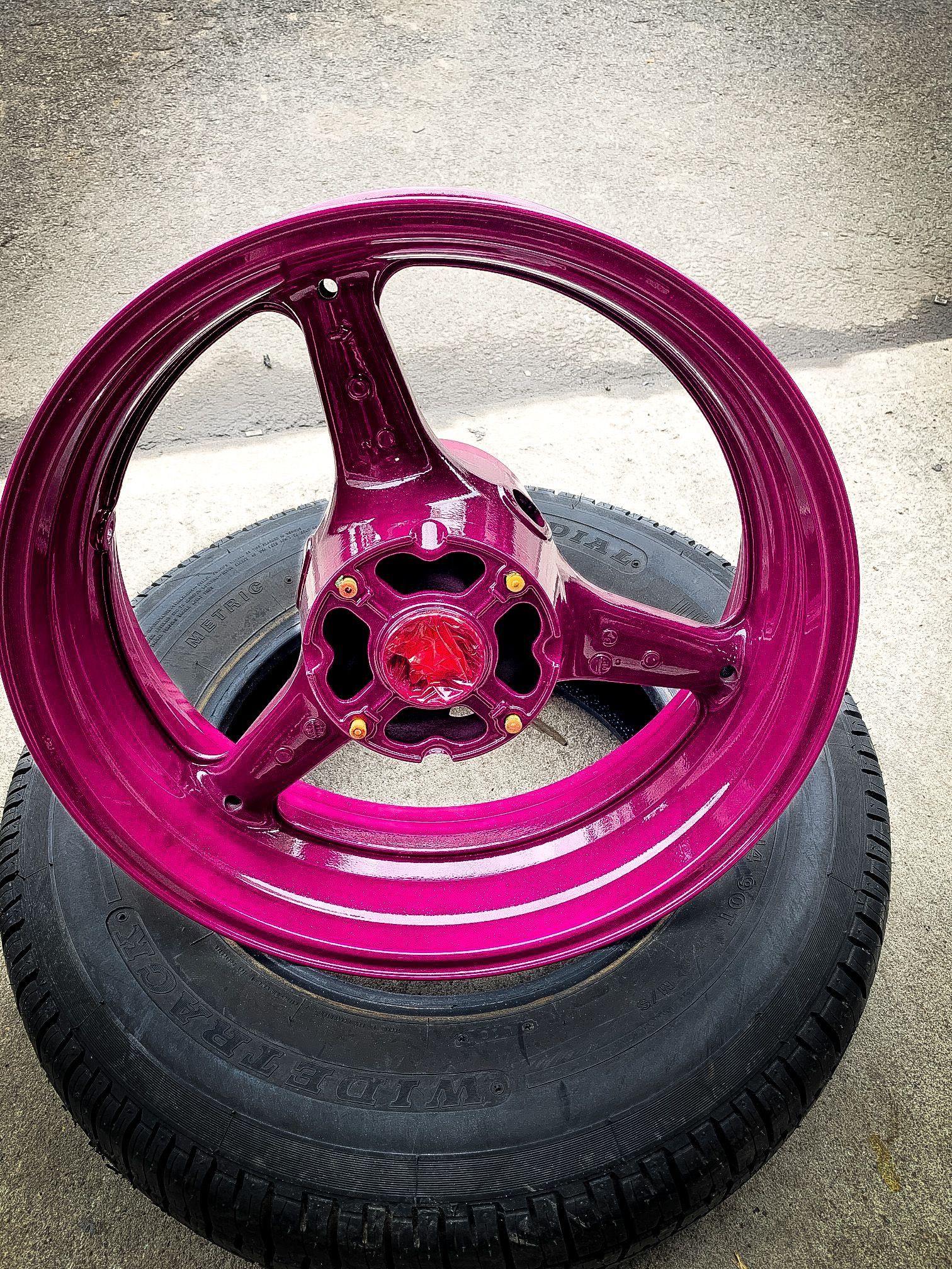 A pink wheel is sitting on top of a tire.
