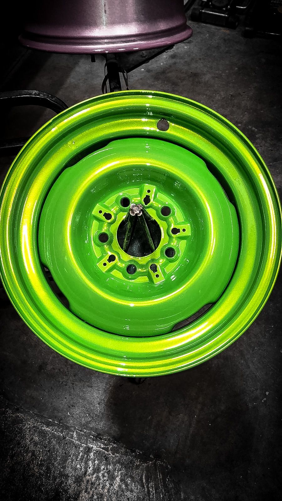 A green wheel is sitting on a black surface.