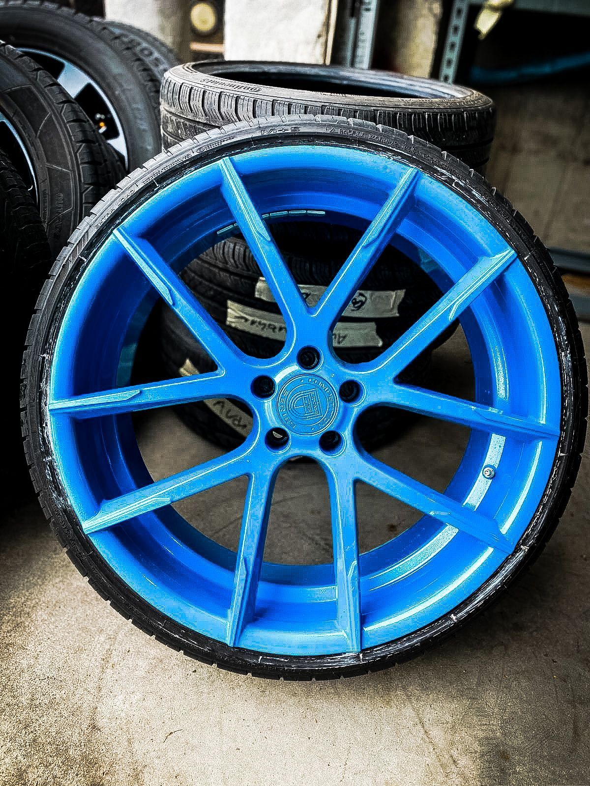 A blue wheel is sitting next to a pile of tires