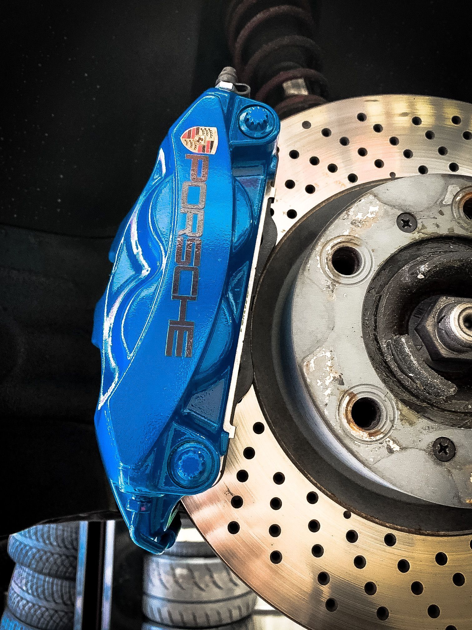 A blue porsche brake caliper sits on a brake disc