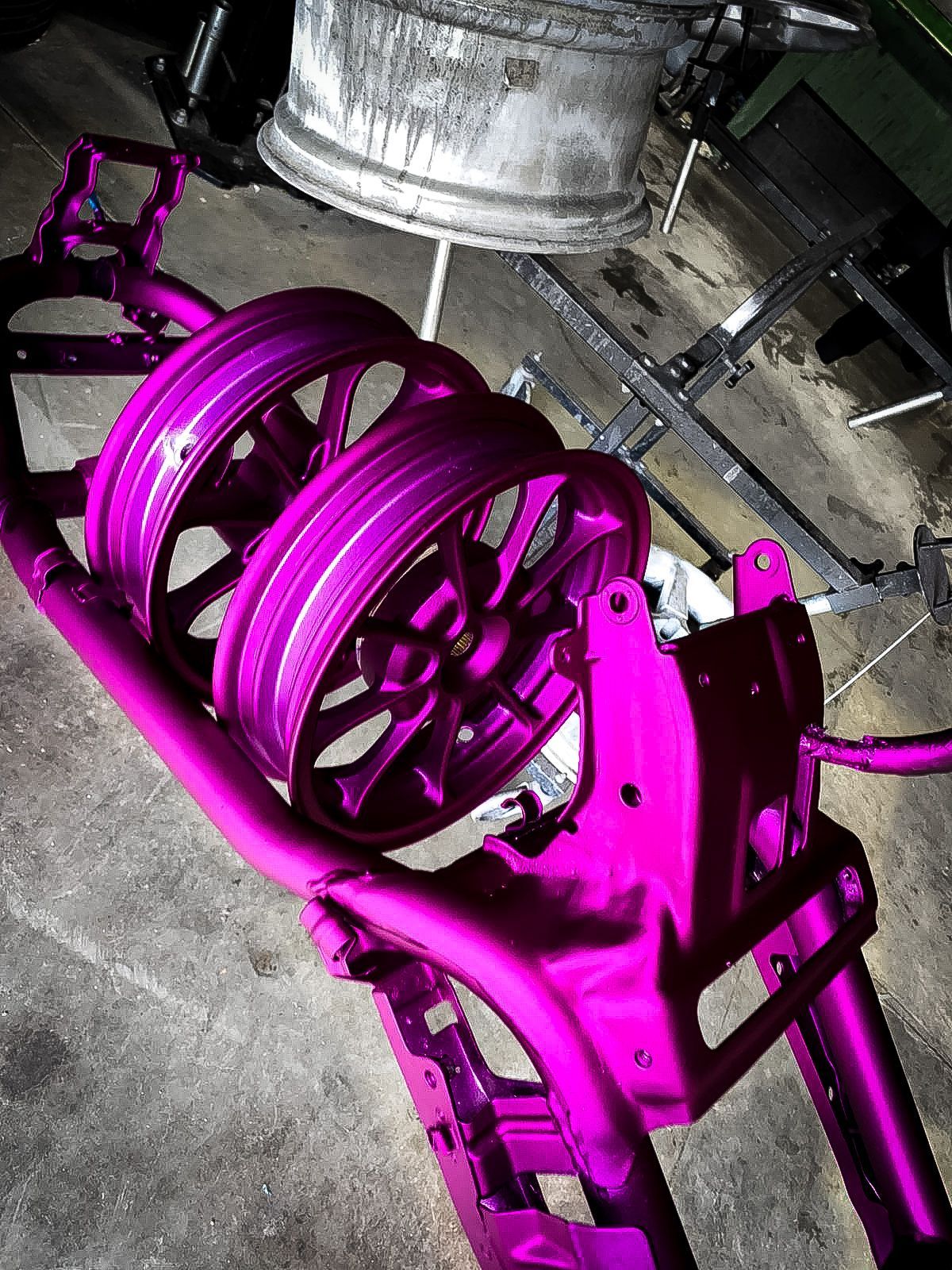 A close up of a pink motorcycle frame with purple wheels.