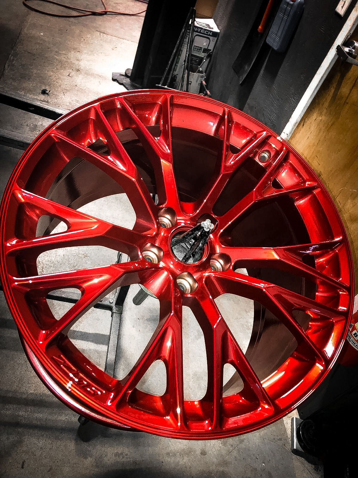 A red wheel is sitting on a table in a garage.