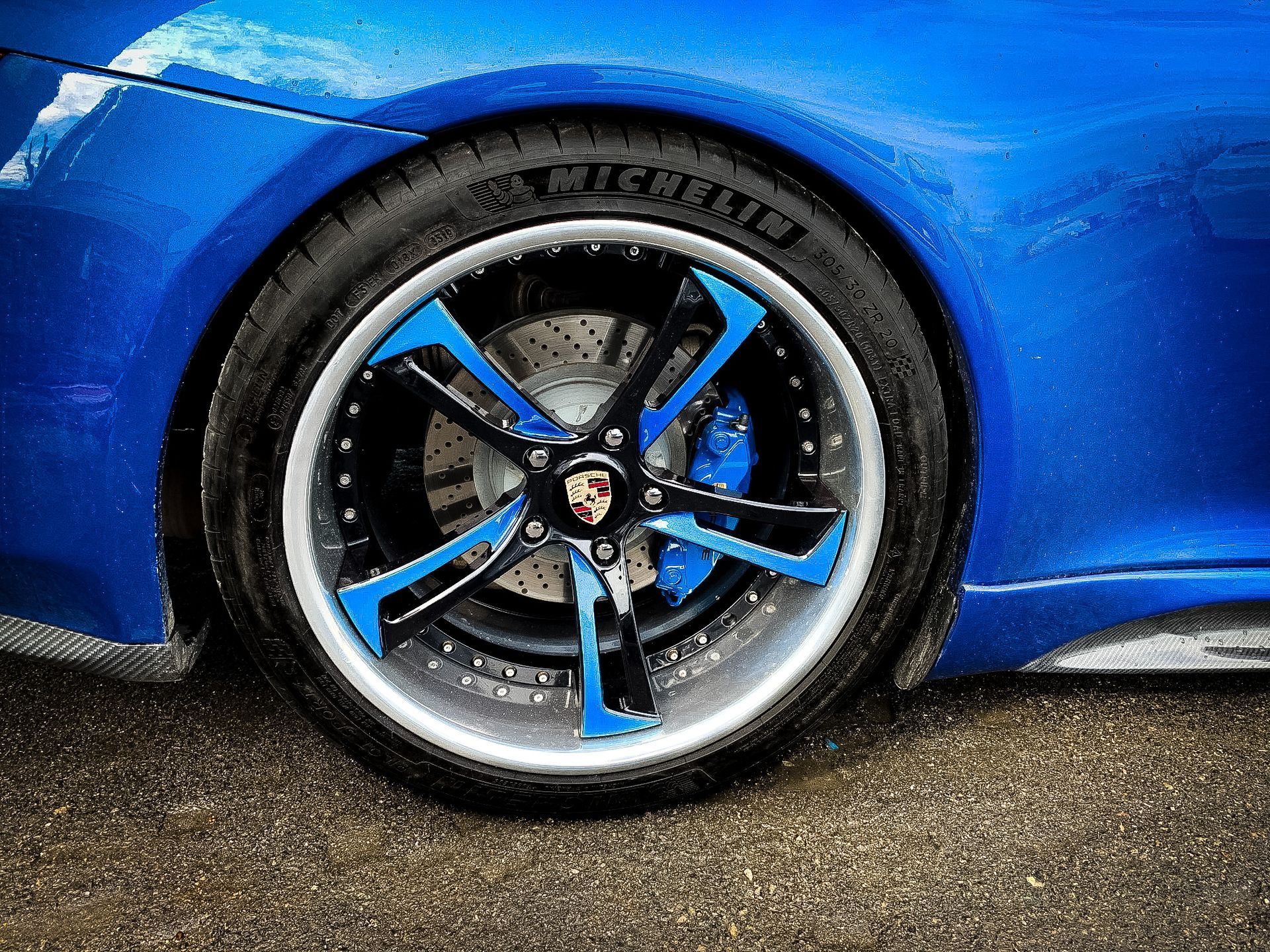 A close up of a blue car wheel with a michelin tire.