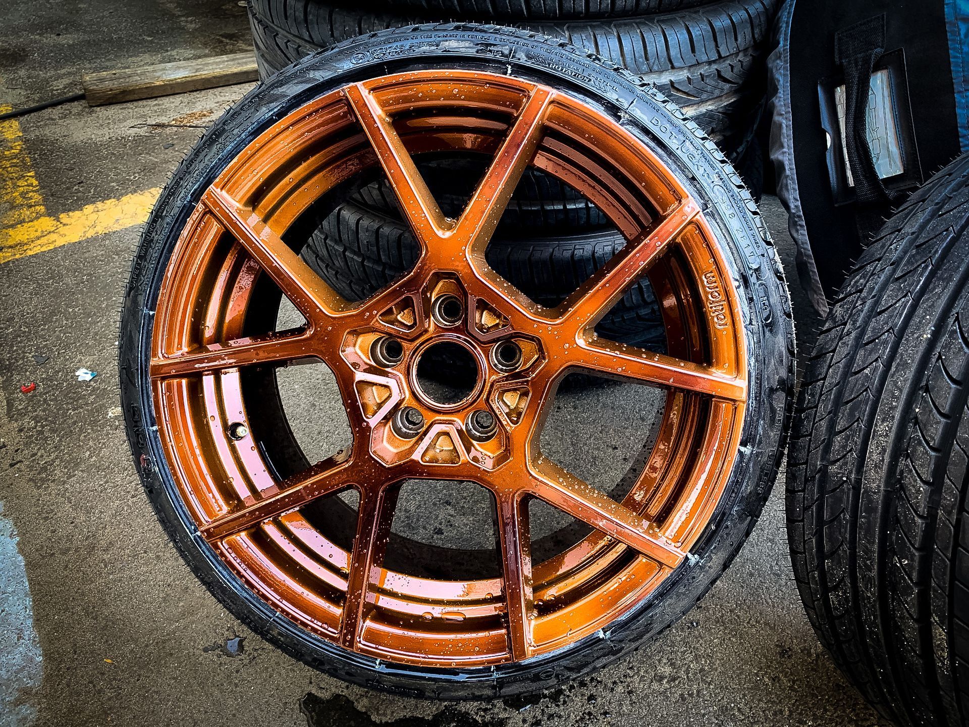 A close up of a wheel with a tire in the background.
