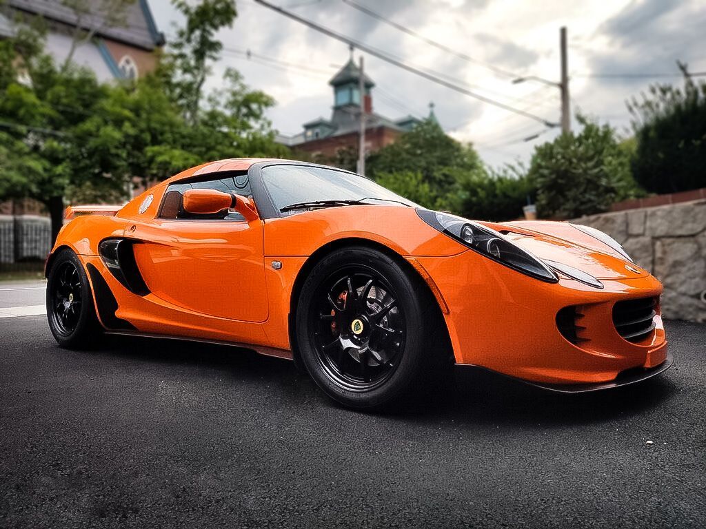 An orange sports car is parked on the side of the road.