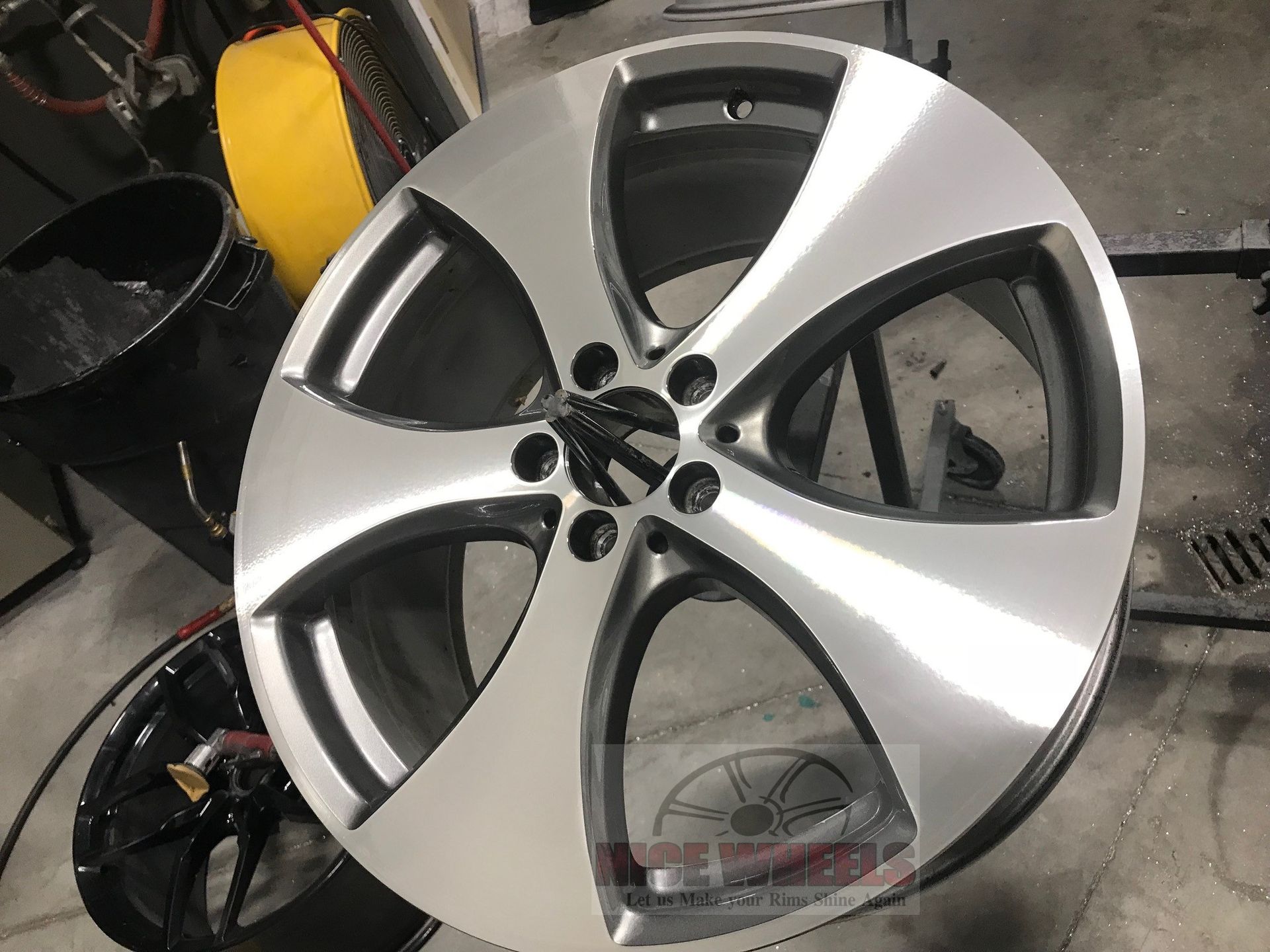 A car wheel is sitting on a table in a garage.