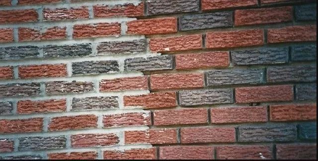 A close-up of a brick wall where a section has been repaired or repointed, showing contrasting lighter and darker mortar.