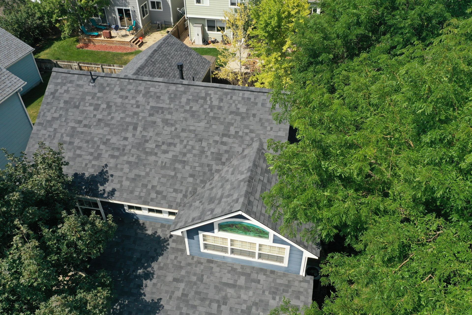 An aerial view of a house with a roof that is surrounded by trees.