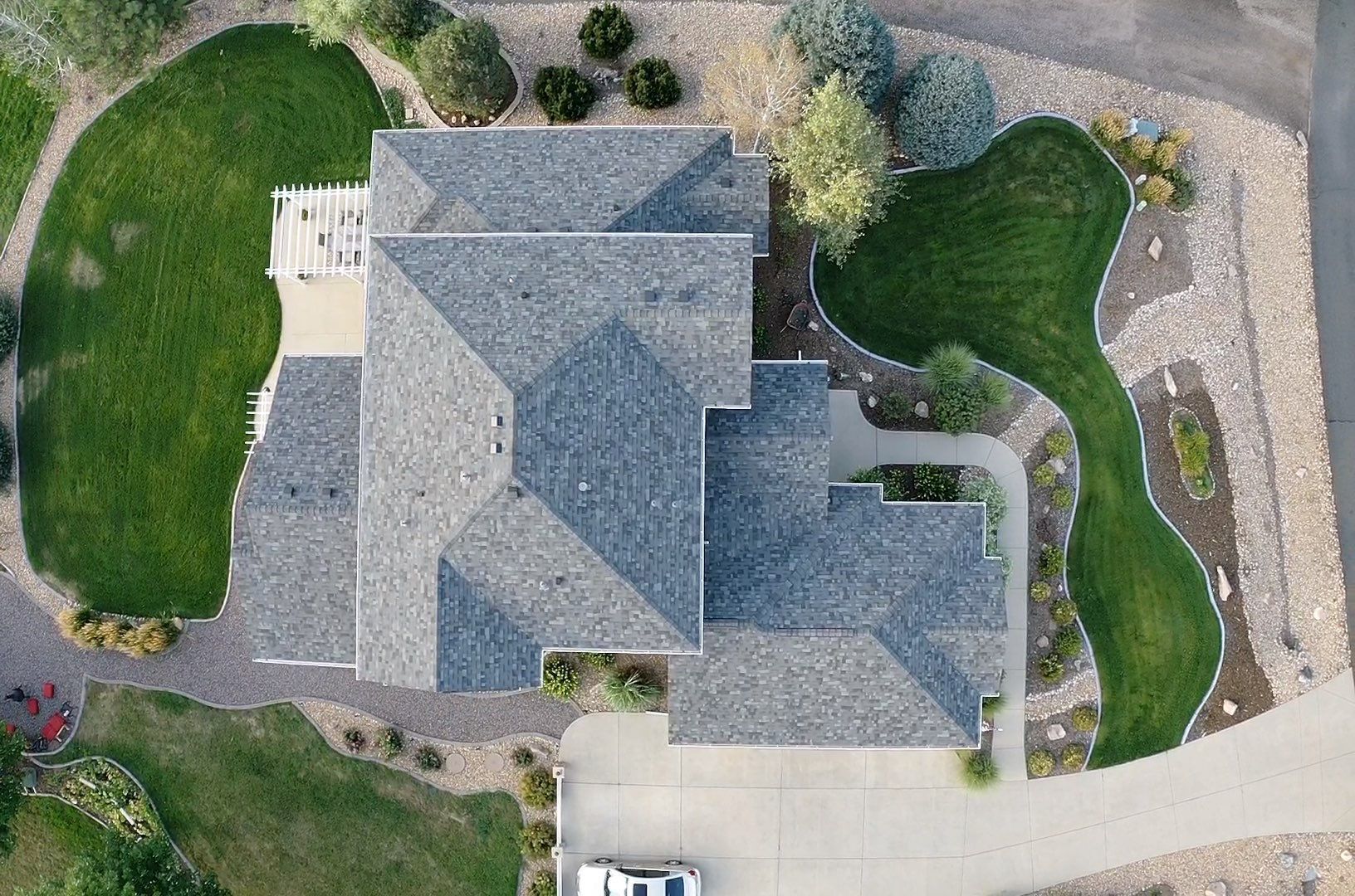 An aerial view of a large house with a lot of grass and a car parked in front of it.