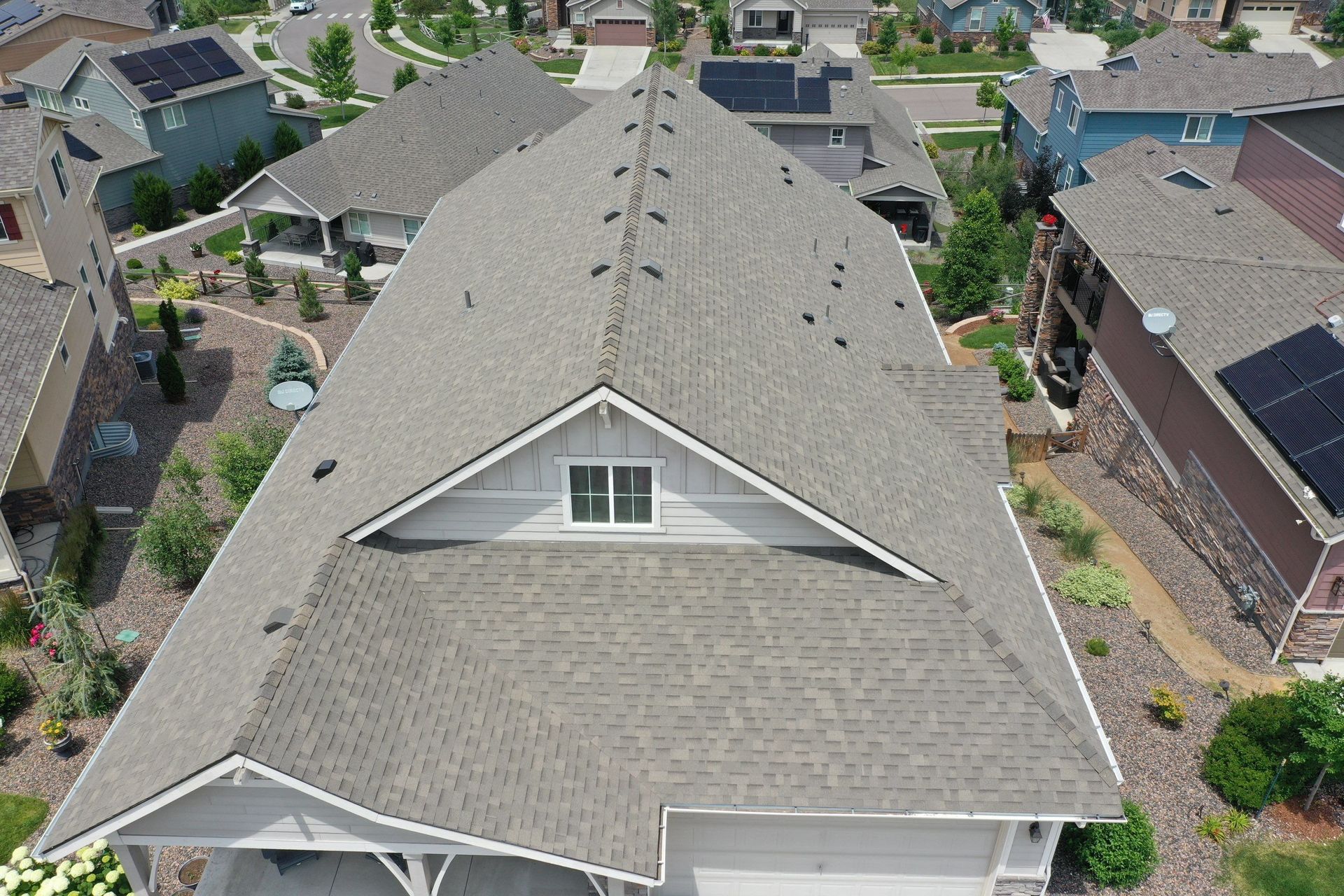 An aerial view of a house with a gray roof in a residential area.