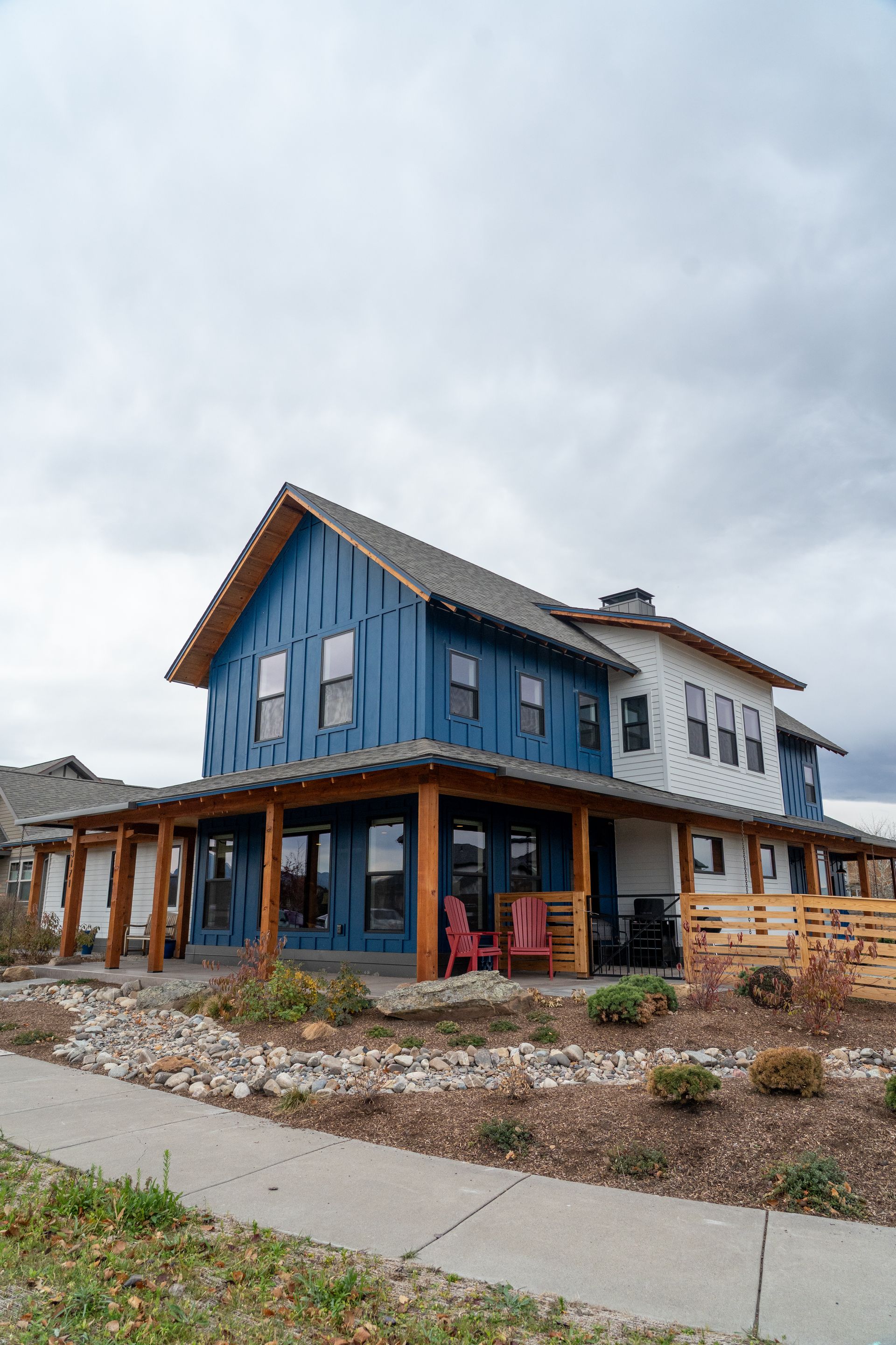 Blue and white two-story house with wraparound porch on a cloudy day