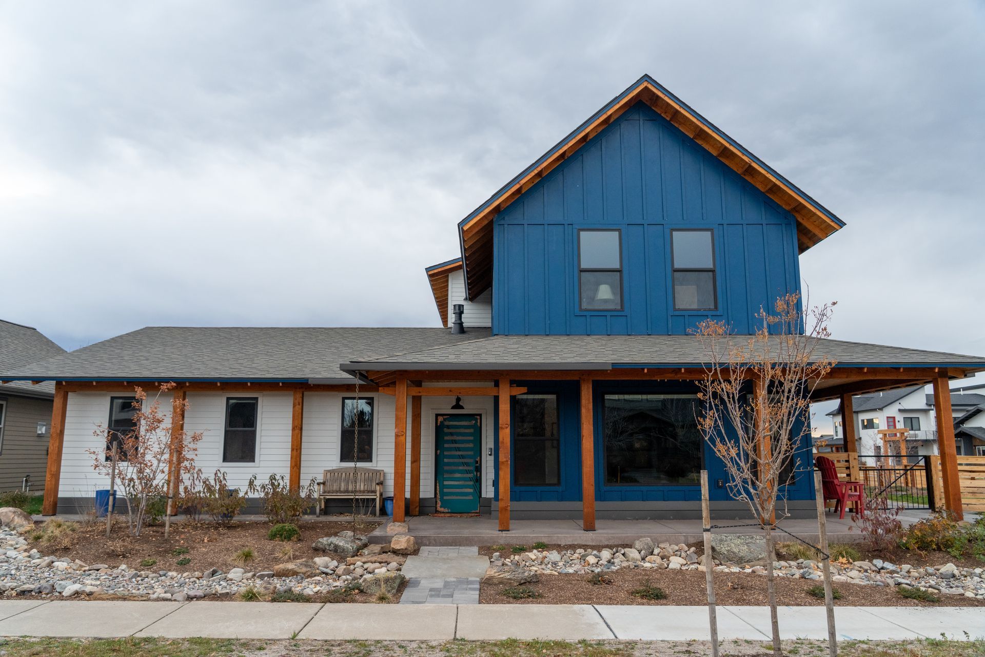 Blue house with a covered porch and stone walkway under a cloudy sky