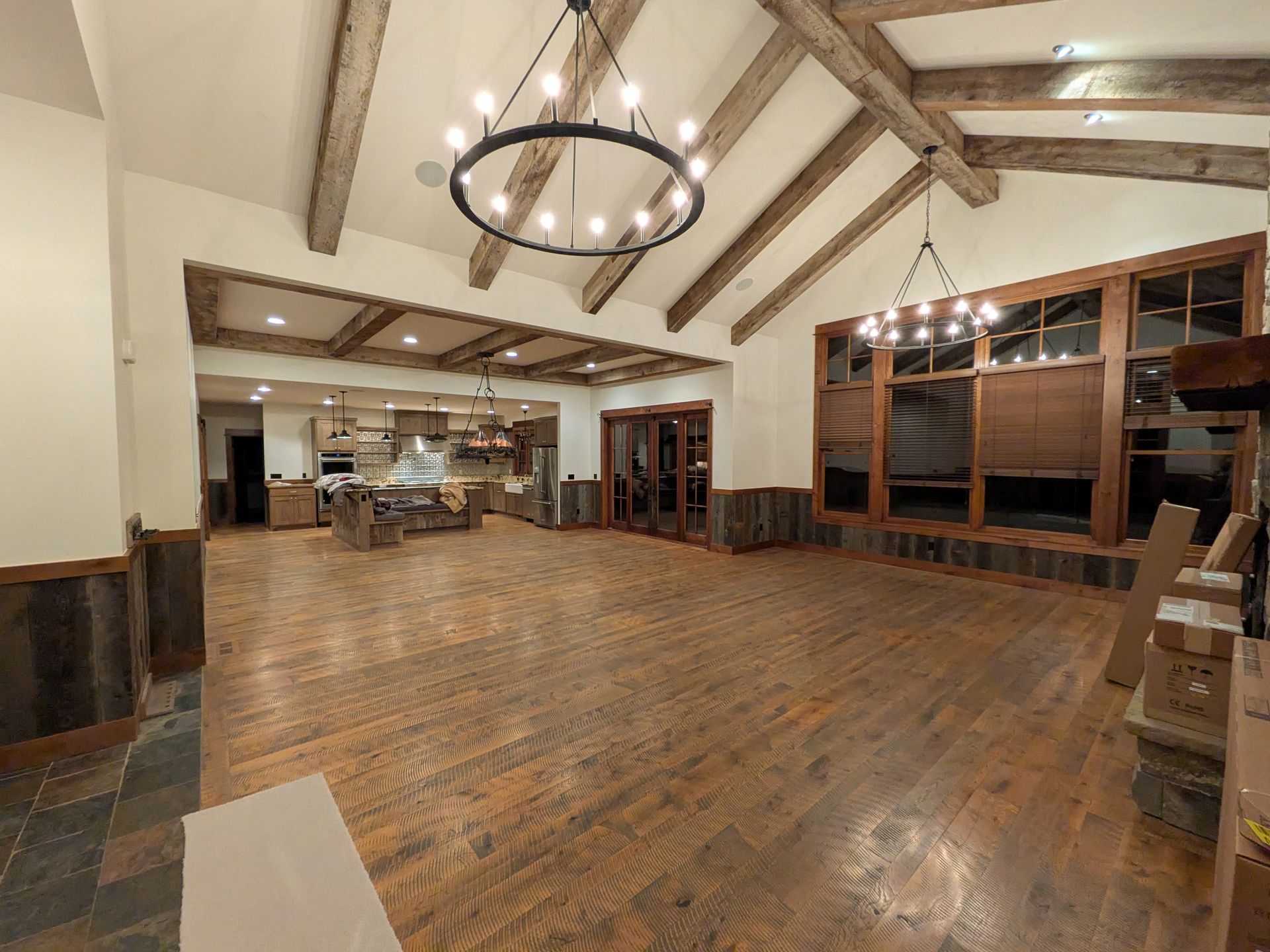 Spacious rustic hall with wood beams, polished floor, and a large circular chandelier