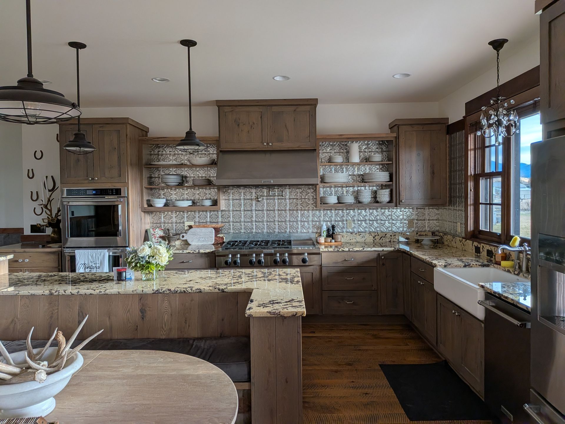 Spacious rustic kitchen with wood cabinets, granite counters, island, farmhouse sink, and large windows