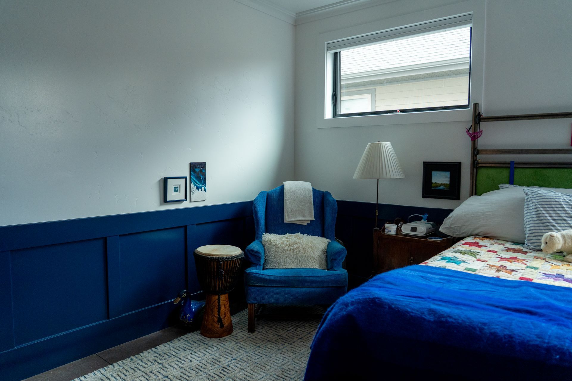 Blue-and-white bedroom with bed, armchair, lamp, and window