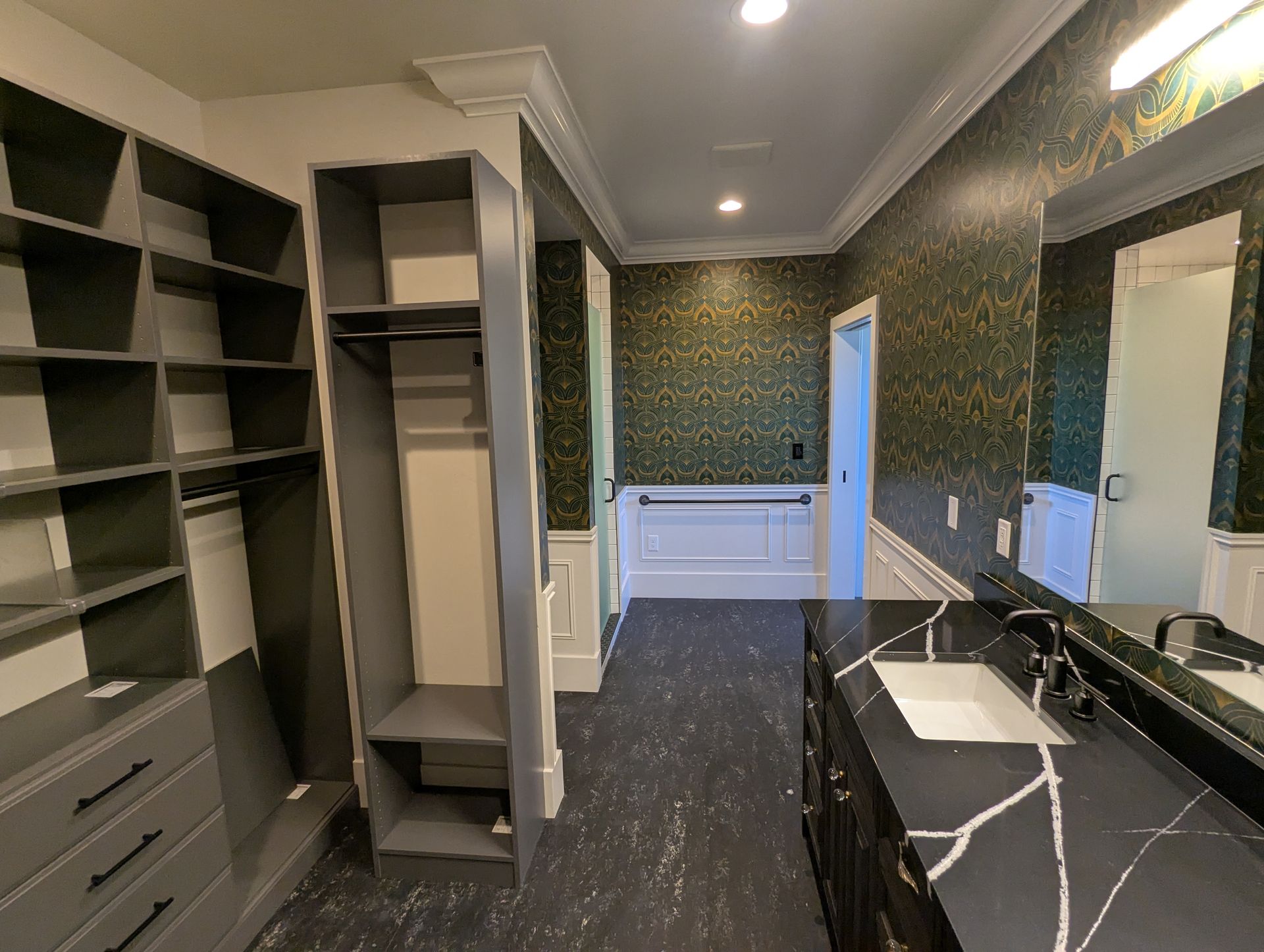 Walk-in closet with open shelving, drawers, a marble-topped vanity, and dark wallpaper