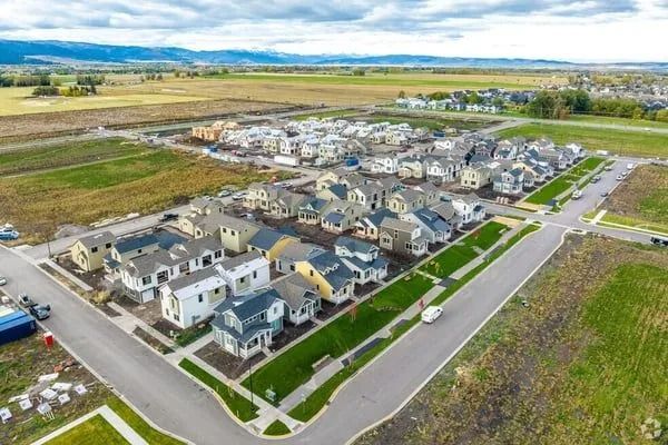 An aerial view of a new suburban residential neighborhood featuring rows of modern houses and streets under a cloudy sky.