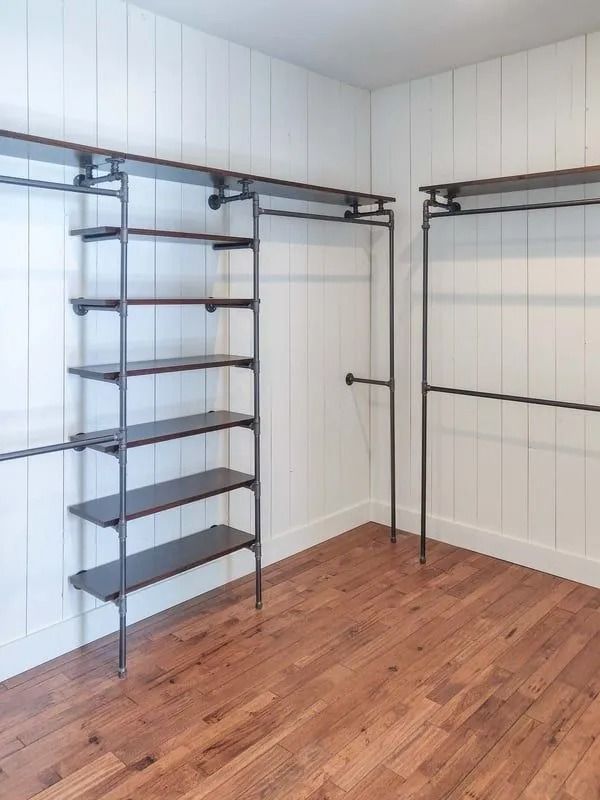 Industrial-style closet featuring dark wood shelves and black metal pipe frames against white shiplap walls.