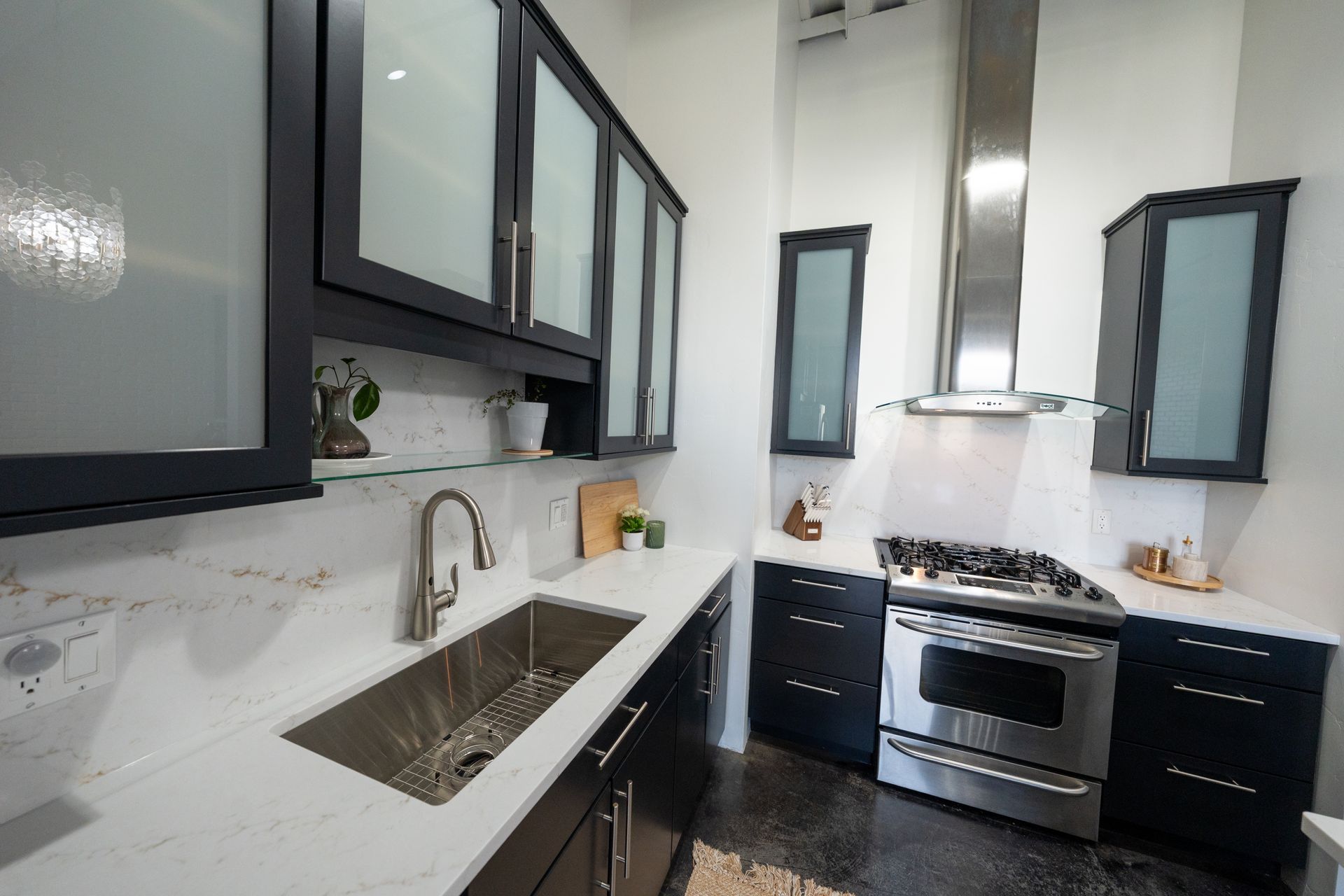 Modern white kitchen with black cabinets, stainless stove, sink, and small windows above the counter.