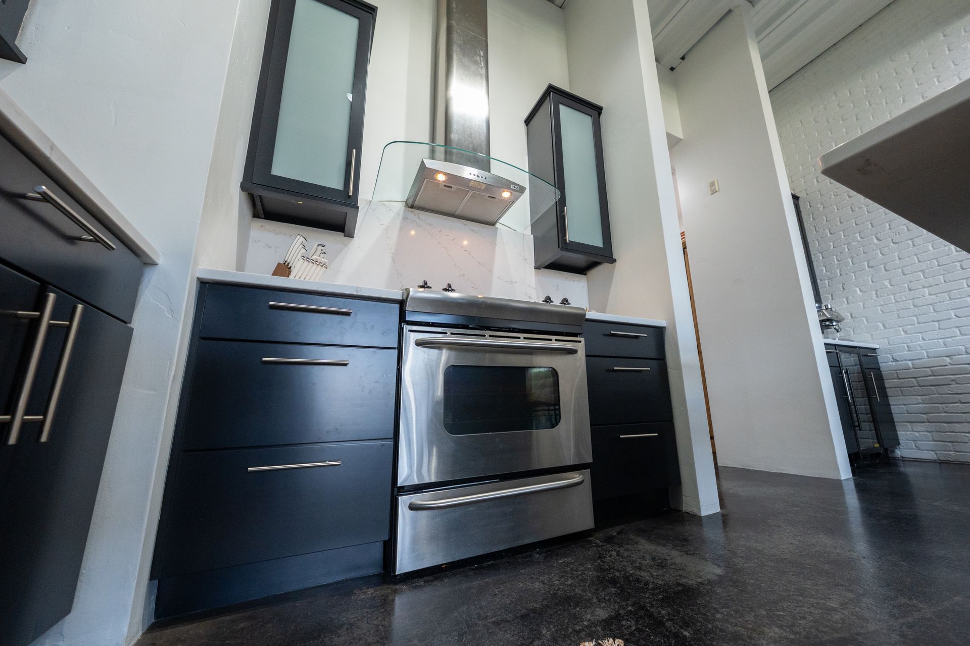 Modern kitchen with stainless steel stove, dark cabinets, and black countertops