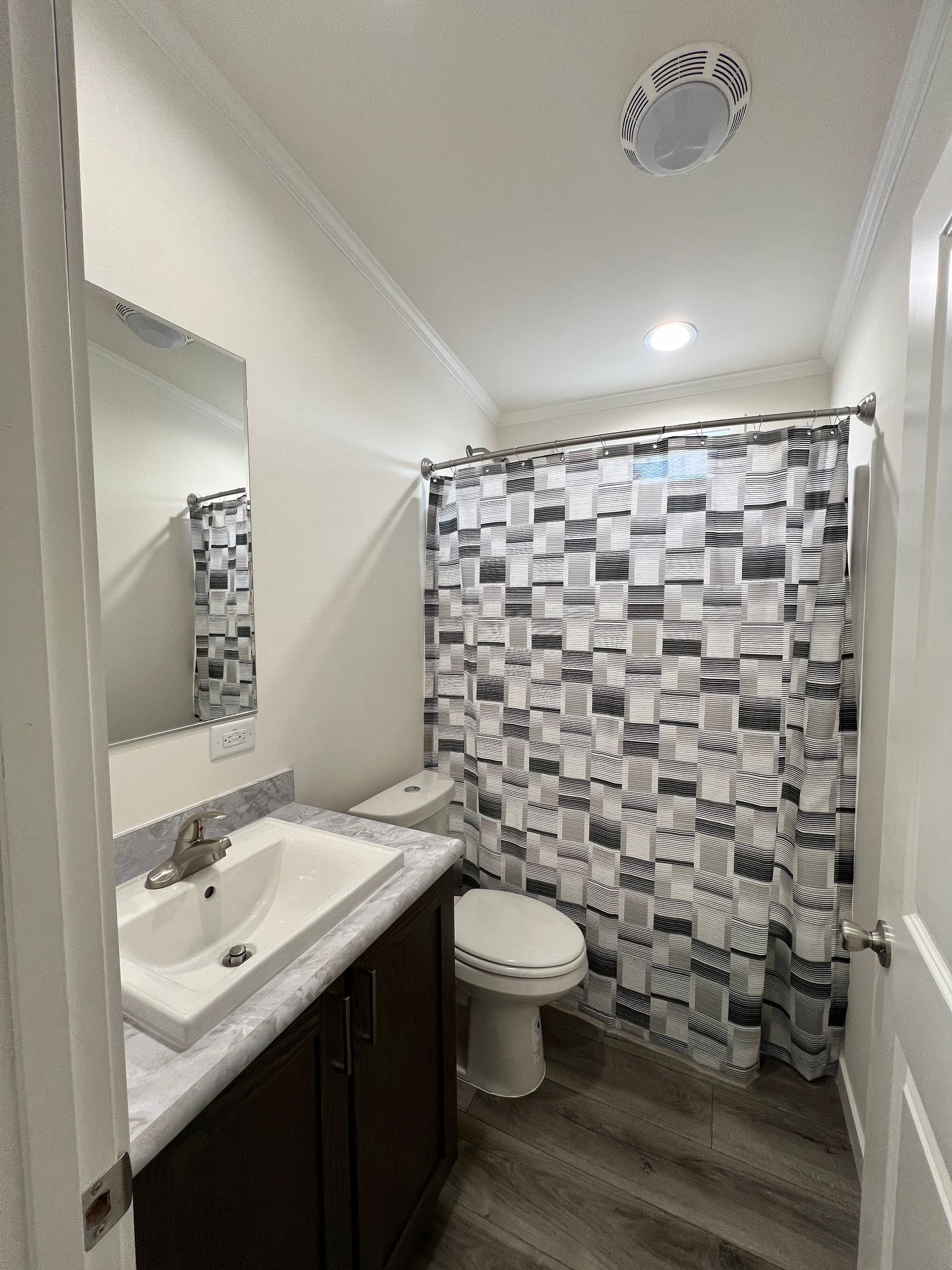Bathroom with toilet, sink, and patterned shower curtain.