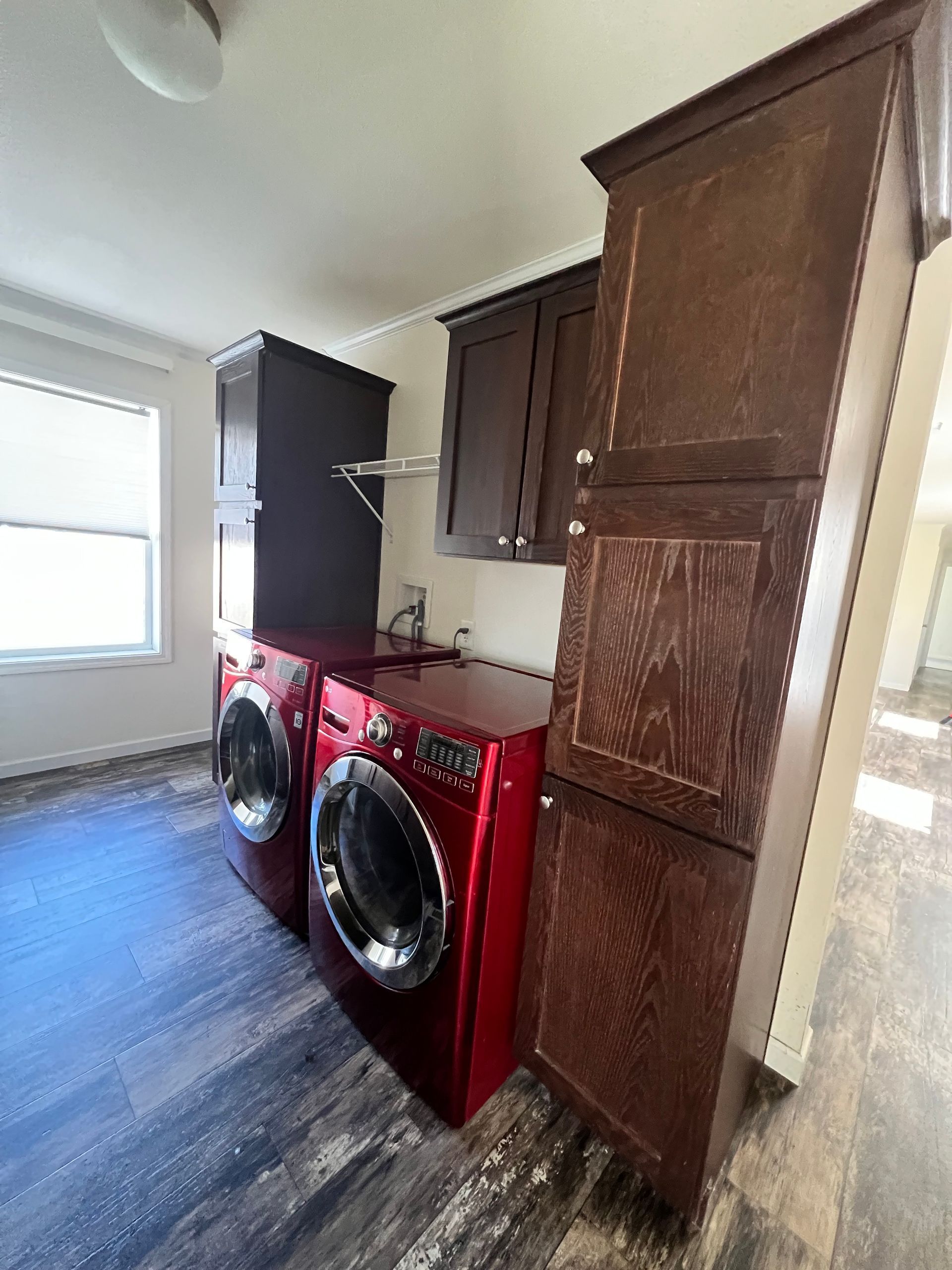 Red washing machine and dryer with dark cabinets in a laundry room.