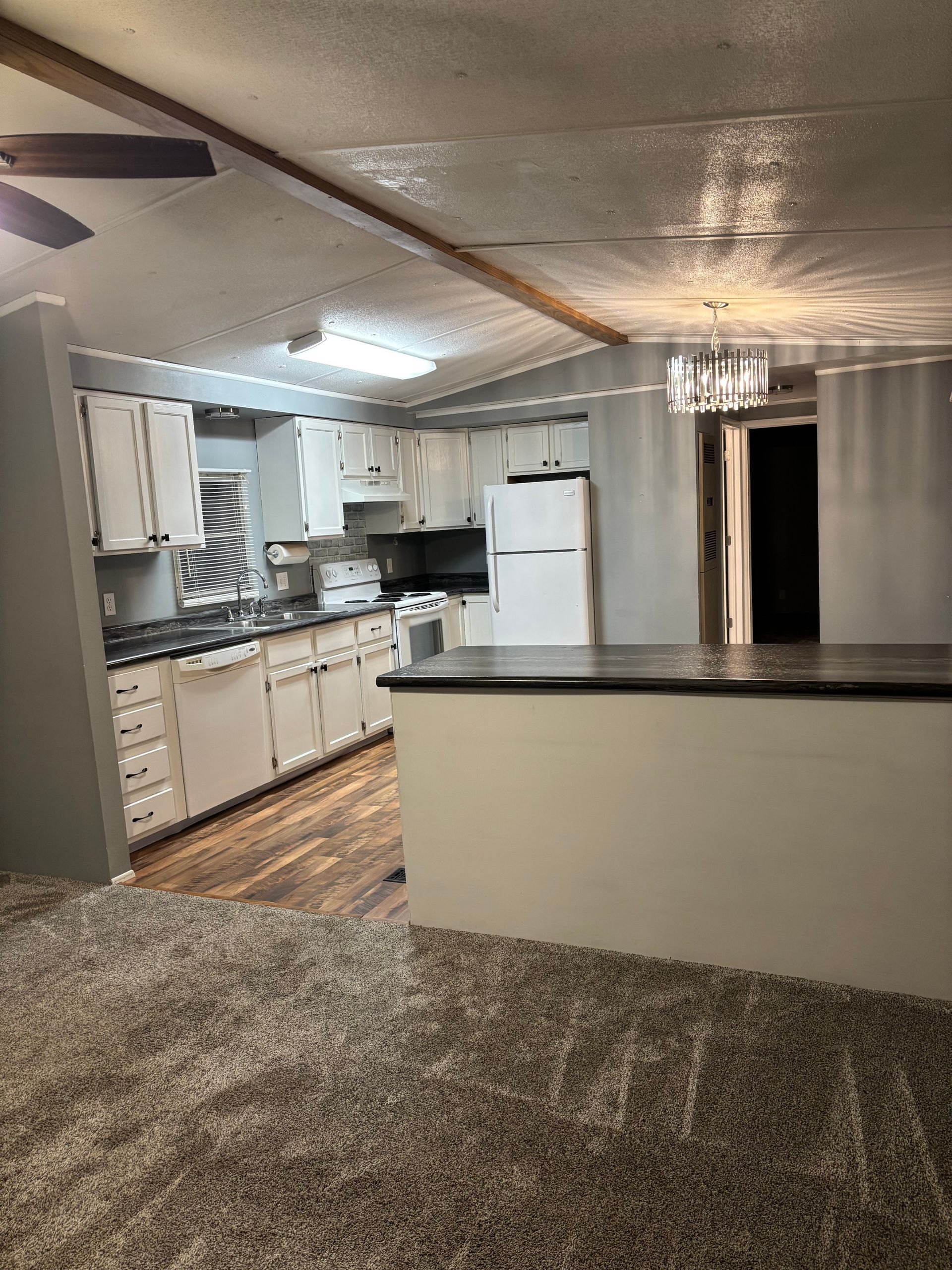 Kitchen area with white cabinets, dark countertop, and breakfast bar. Neutral walls and flooring.