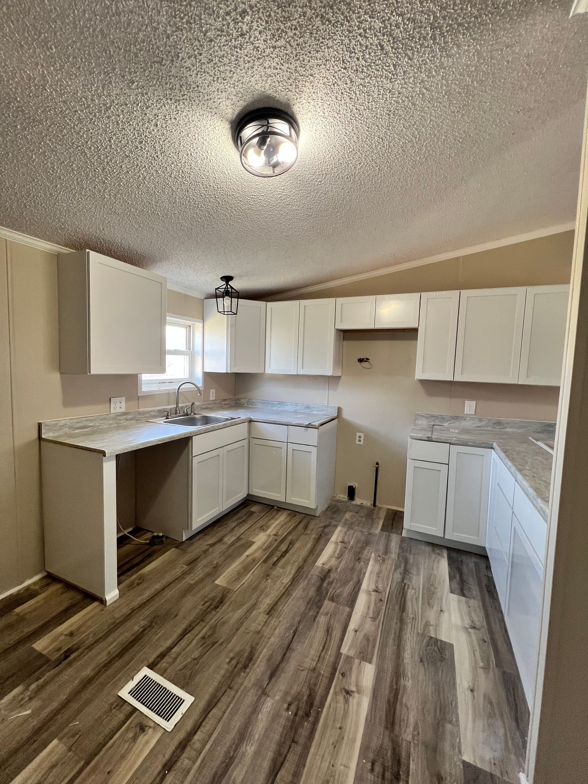 Kitchen with white cabinets, gray countertops, and wood-look flooring.