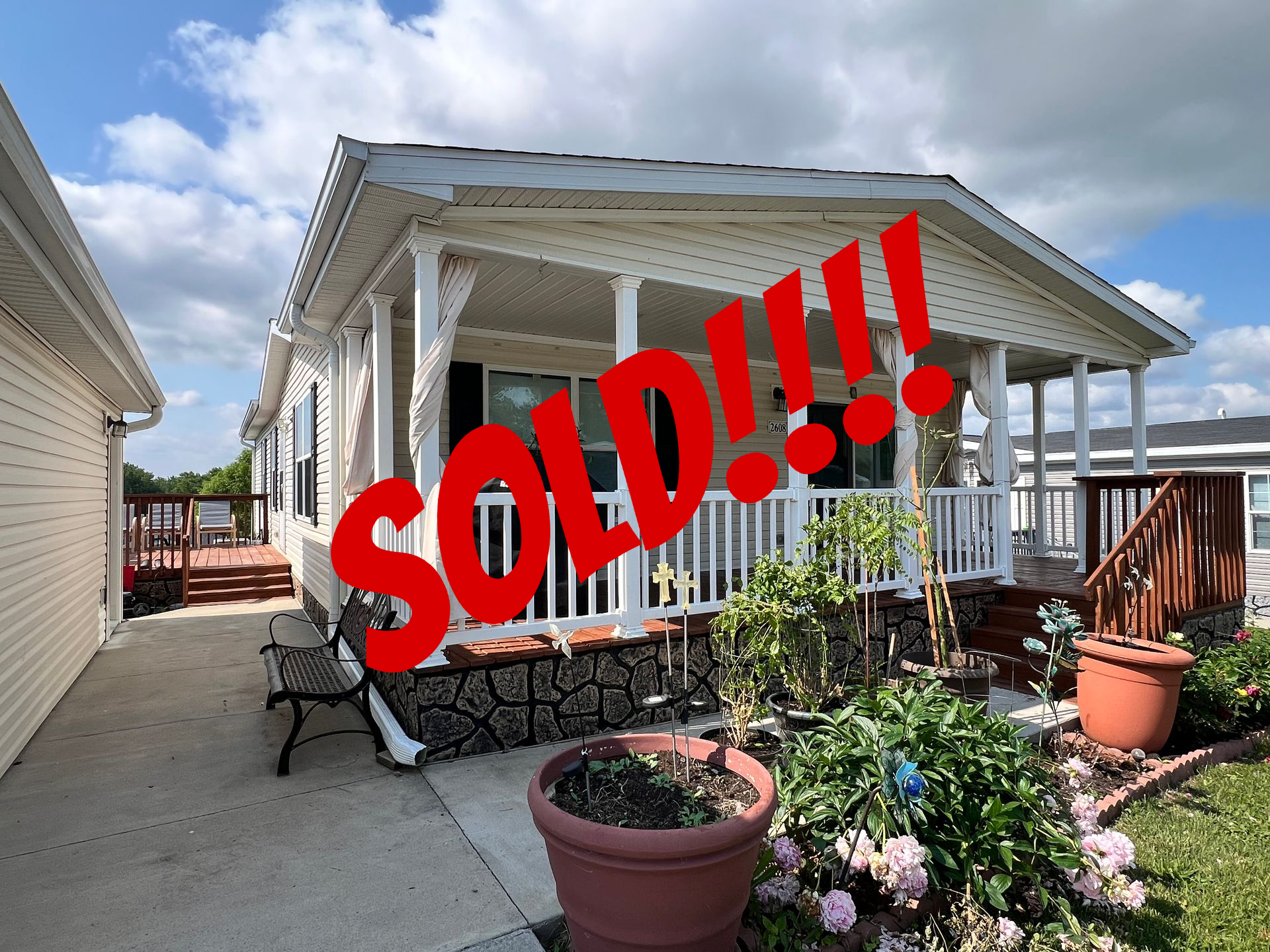 House with a covered porch and detached garage on a sunny day.