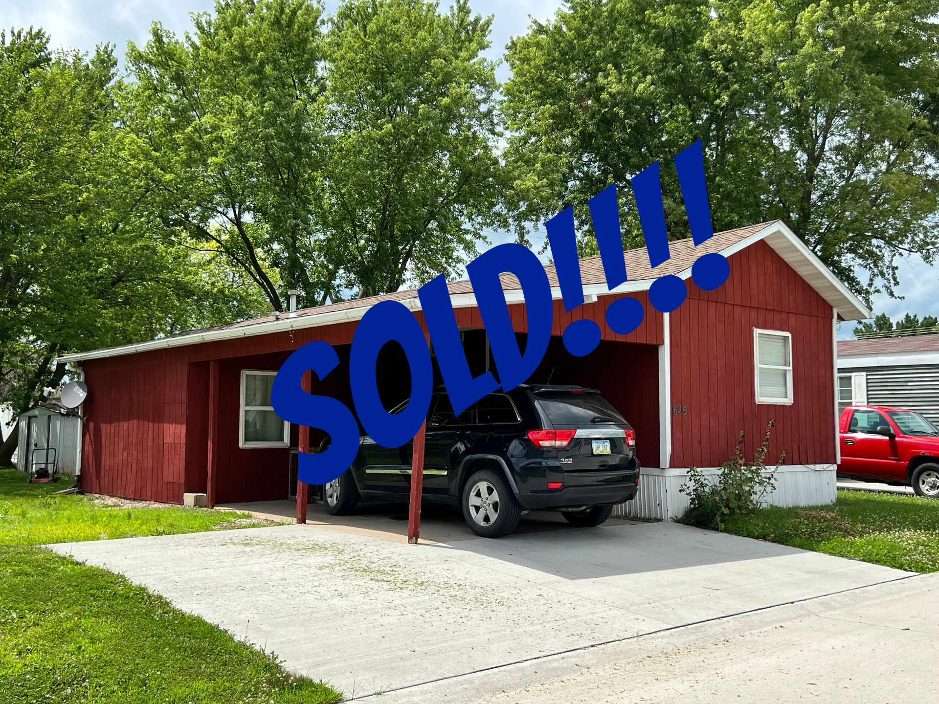 Tan mobile home with brown shutters and skirting on green grass.