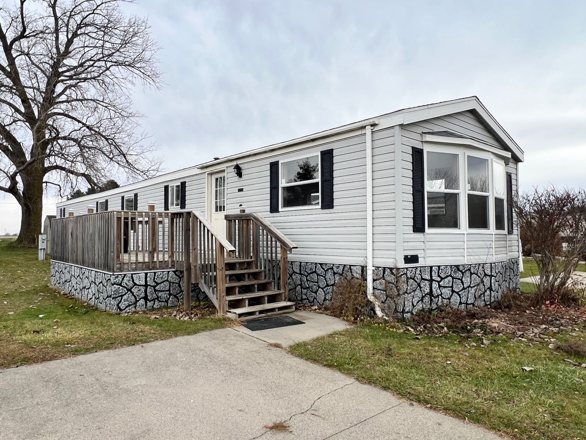 White house with light blue sky, dark pink bushes, and a concrete driveway.