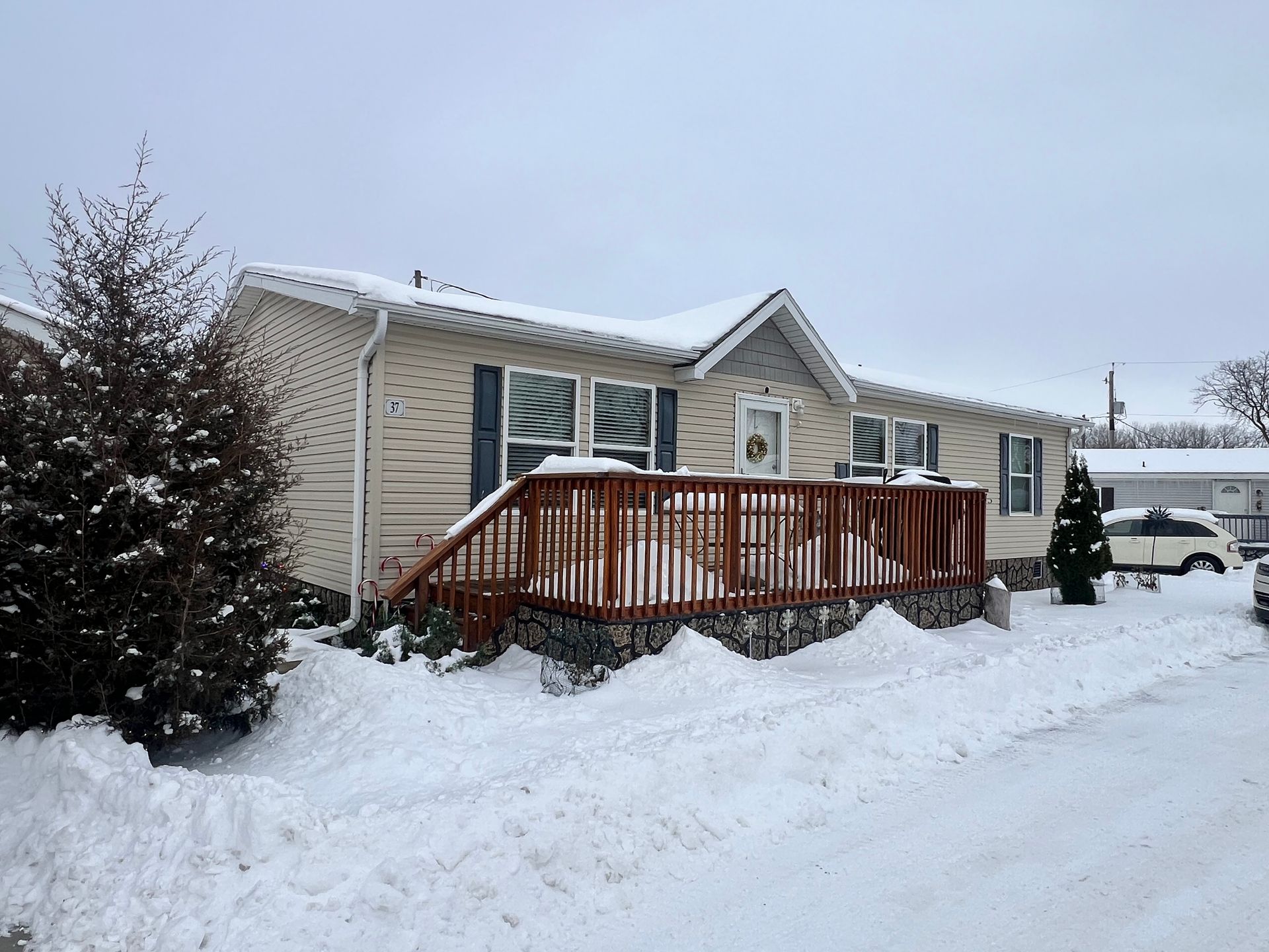 White mobile home with stone-patterned skirting and wooden steps leading to the front door.
