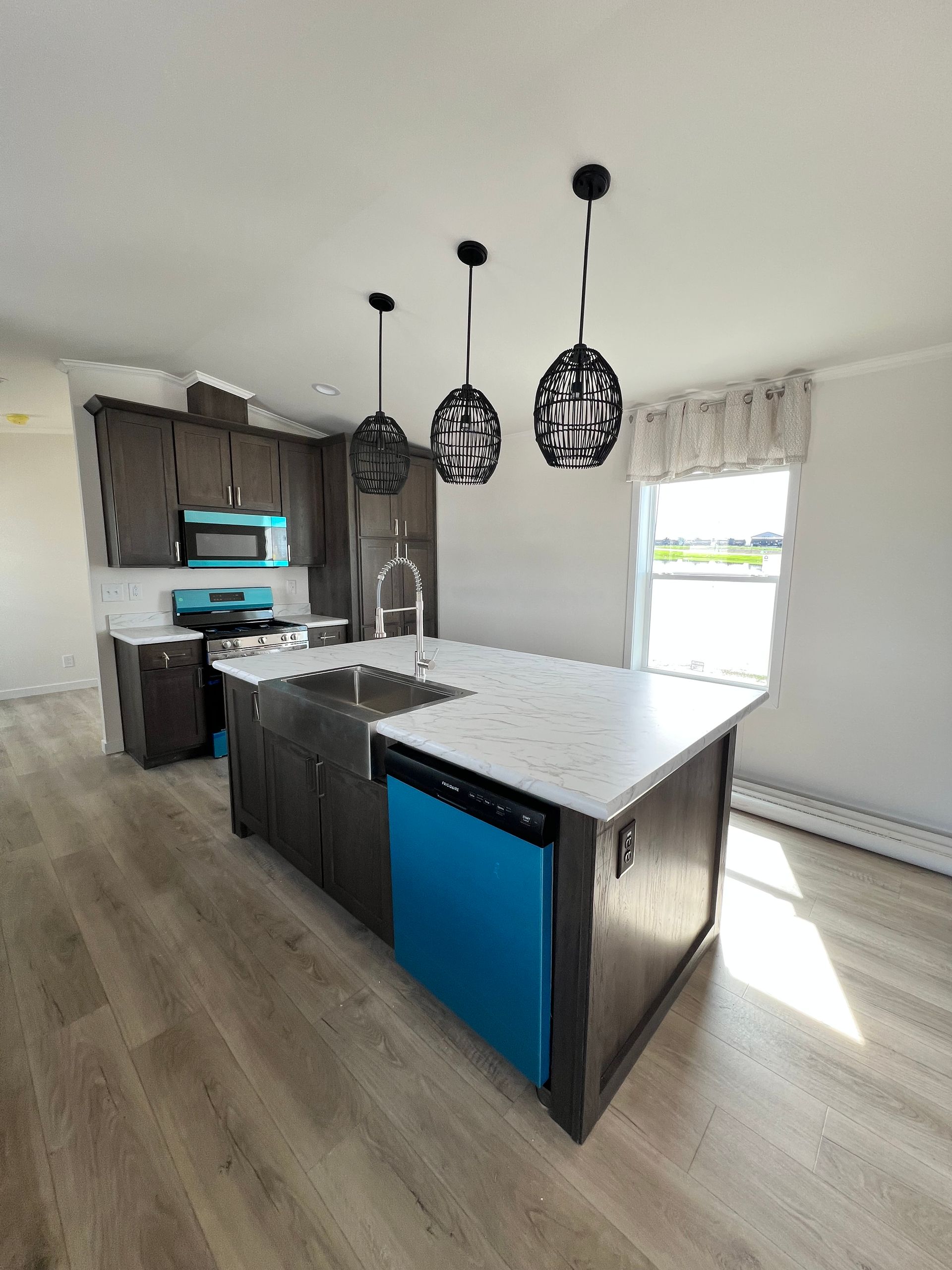 Gray manufactured home on a concrete surface, with white trim and a blue sky.