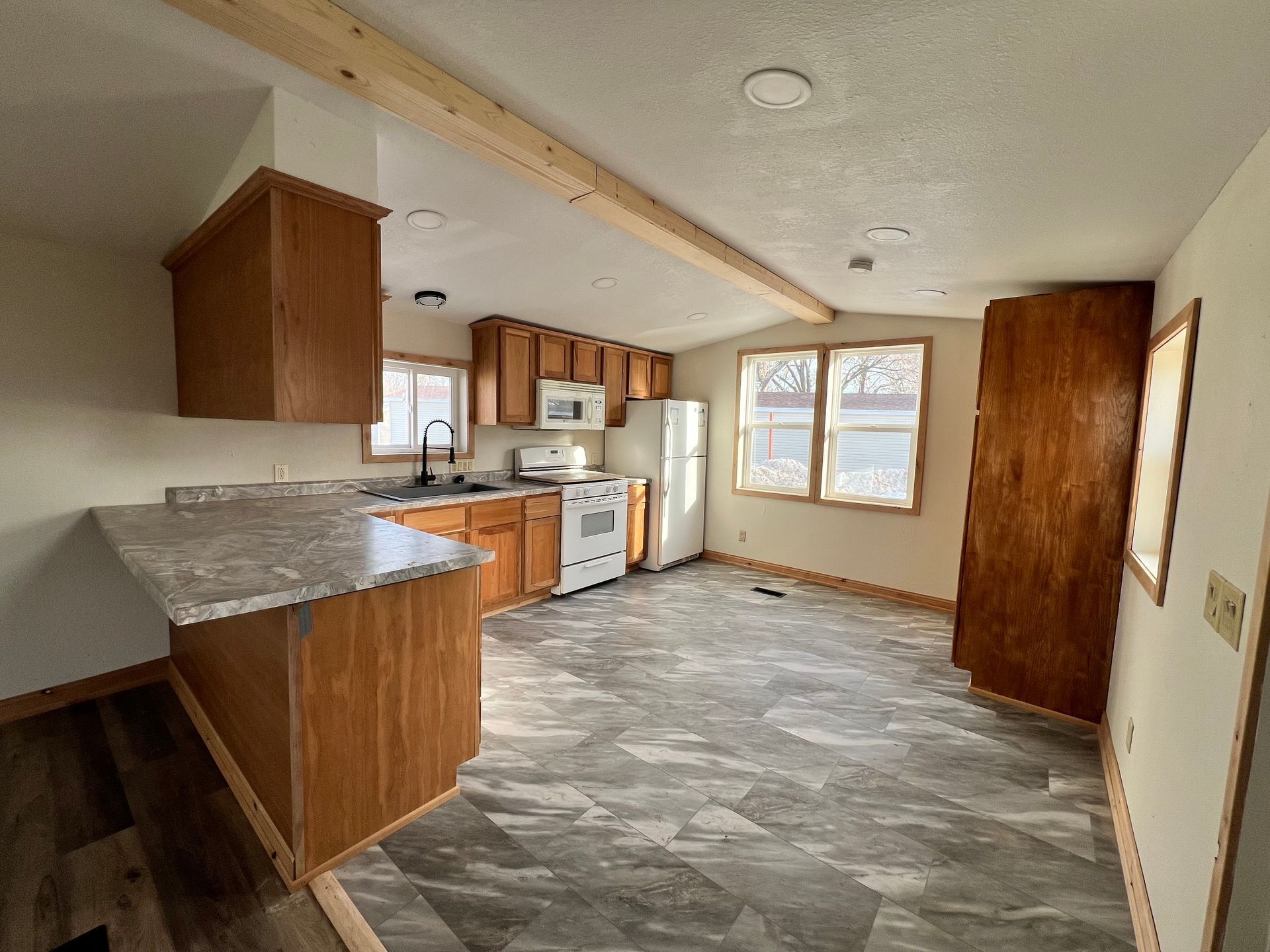 Kitchen with wood cabinets, white appliances, gray countertops, and flooring.