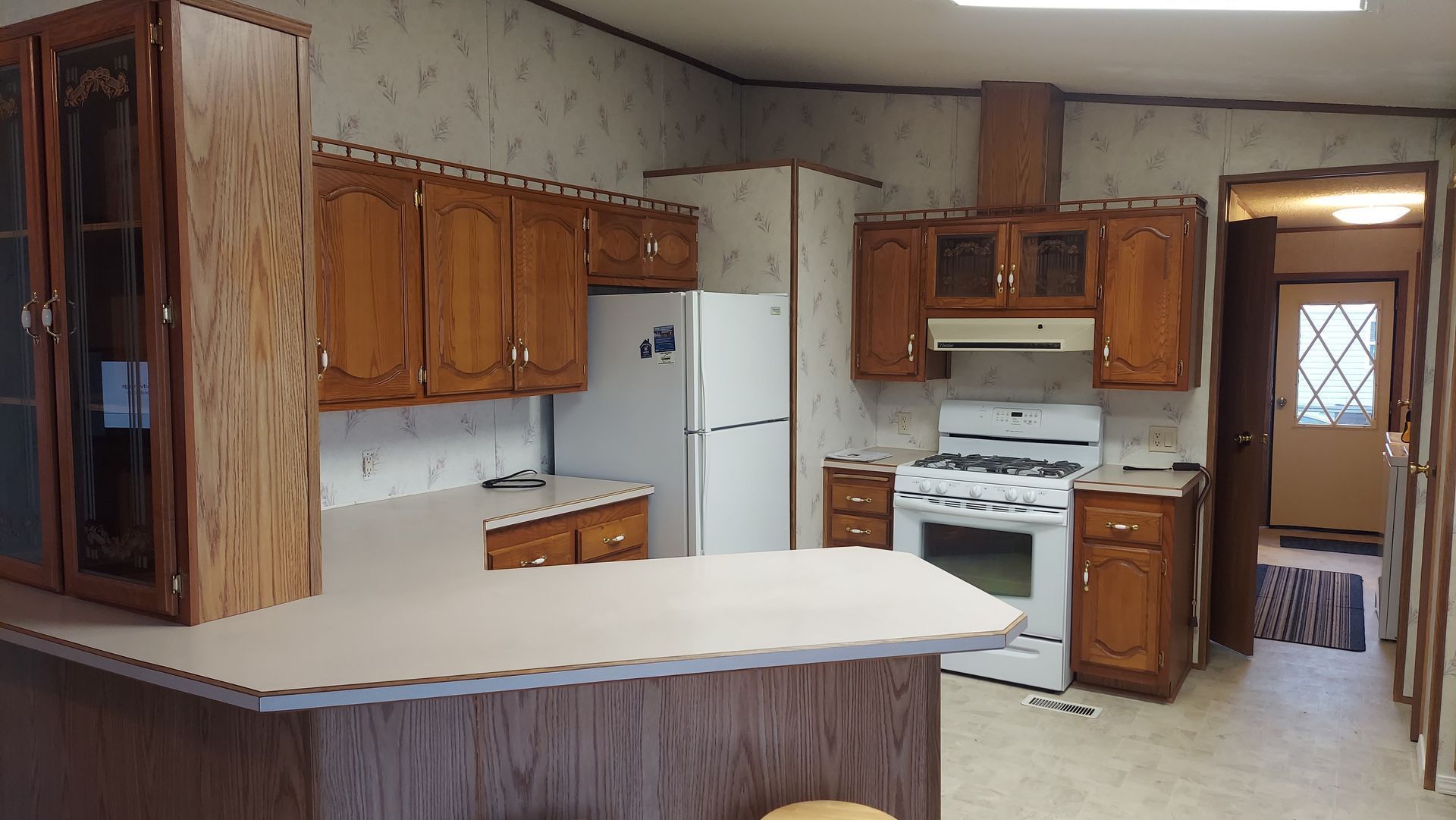 Kitchen with wooden cabinets, white appliances, and a counter.
