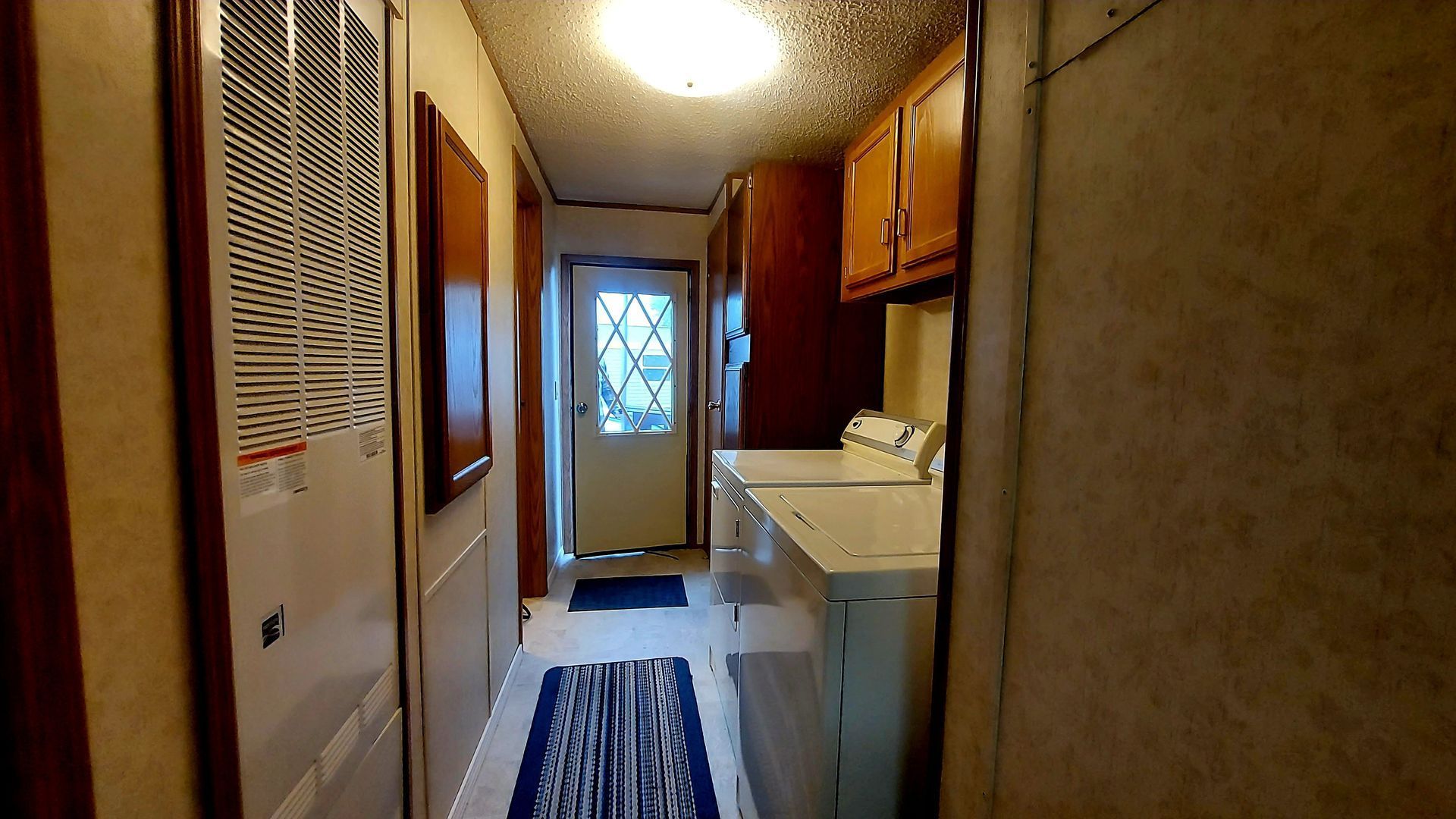 Narrow laundry room with a washing machine, door, and cabinets.
