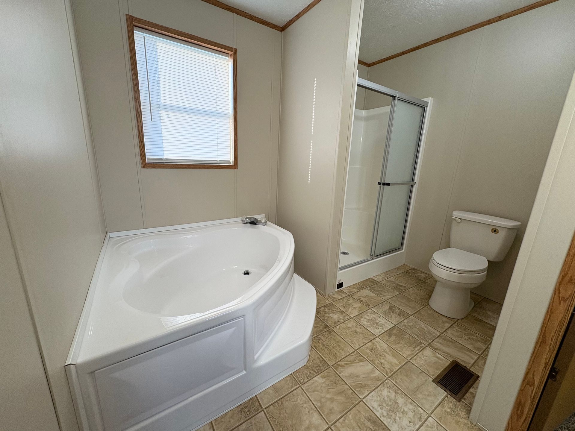 Bathroom with corner tub, shower, and toilet; beige walls and tile.