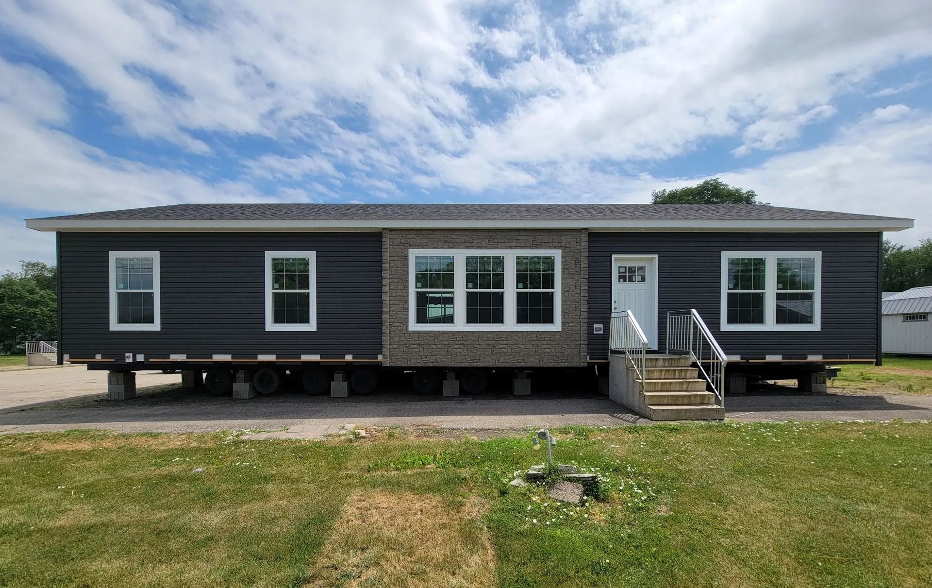 Dark grey manufactured home with light stone detail and white trim, set on foundation.