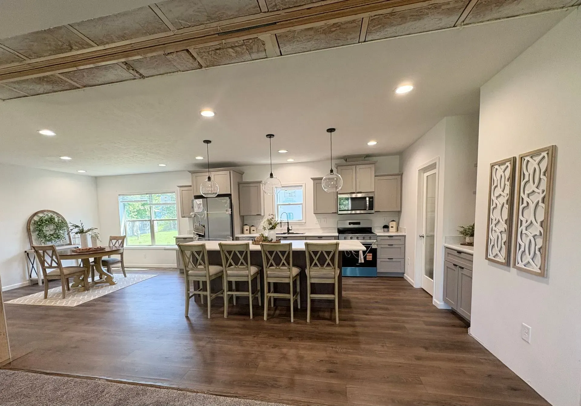 Open-concept kitchen and dining area with gray cabinetry, island seating, and wood-look flooring.