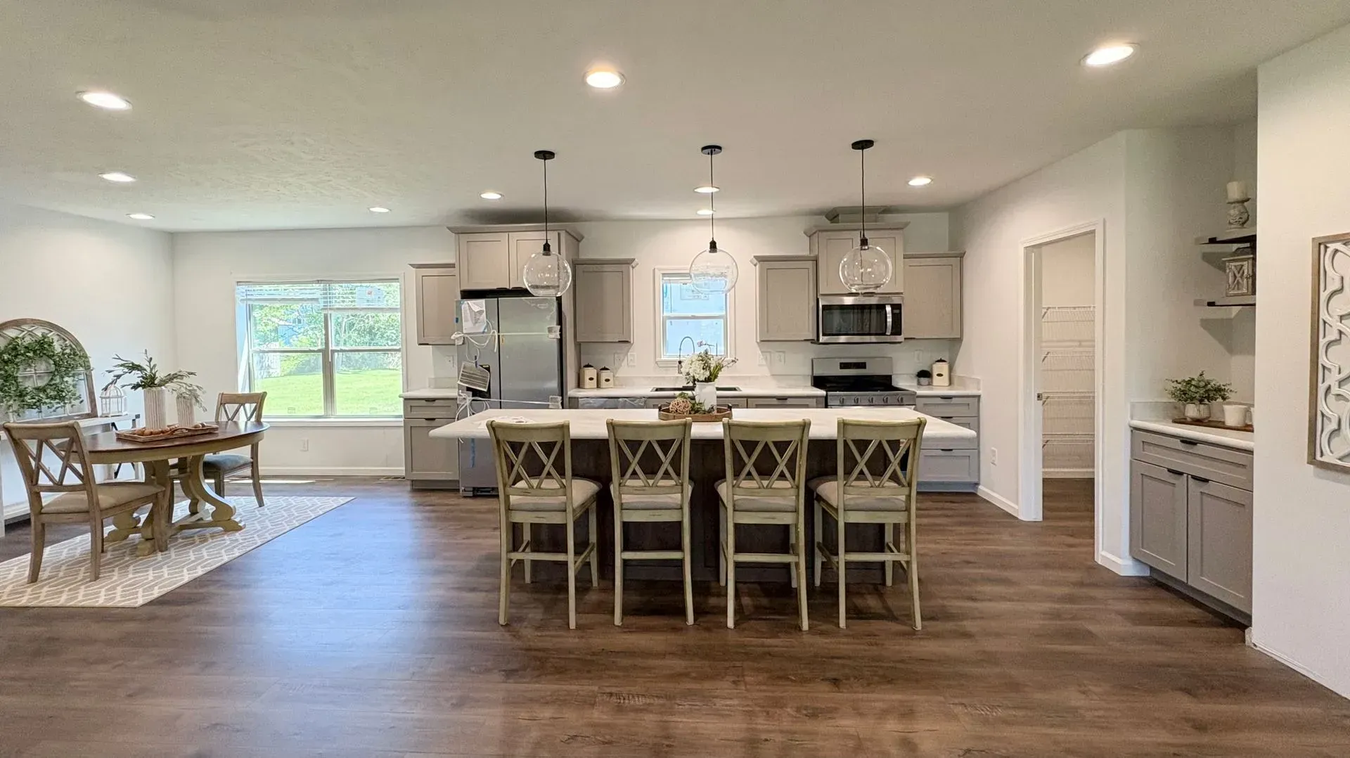 Spacious kitchen with a large island, stainless steel appliances, dining area, and neutral gray cabinets.