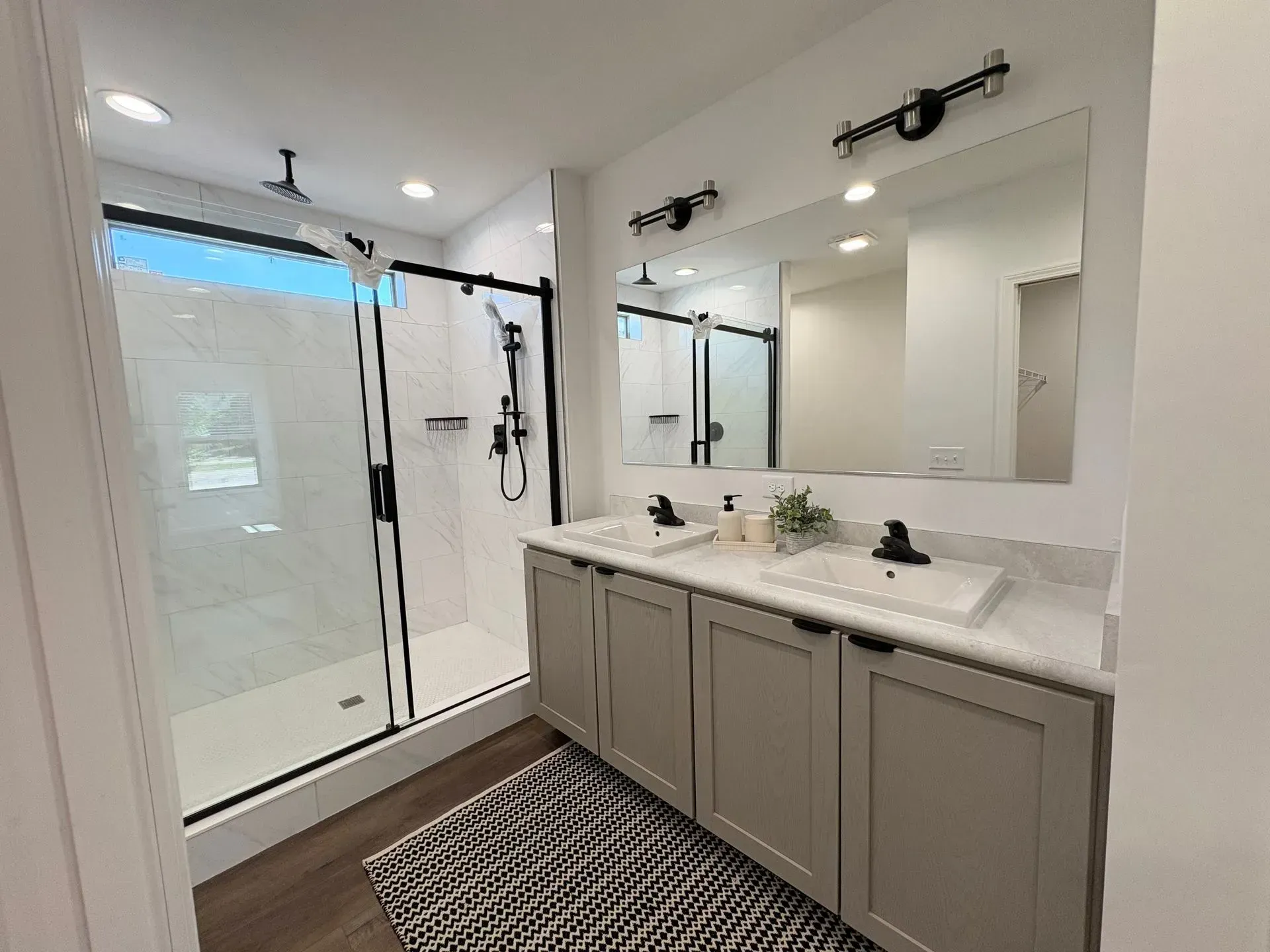 Modern bathroom with a glass shower, double vanity, and dark accents.
