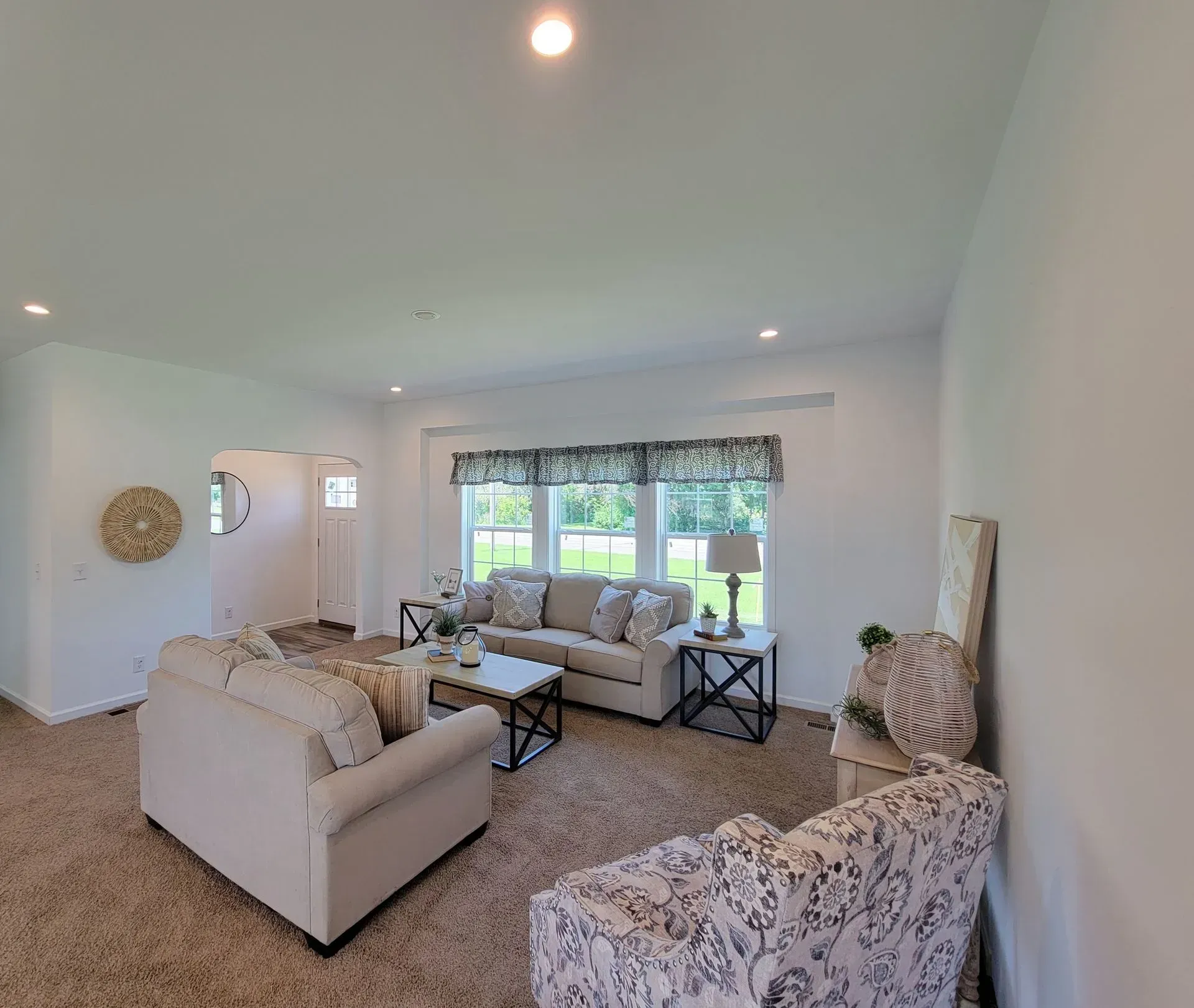 Living room with beige couches, patterned armchair, window, and rug.