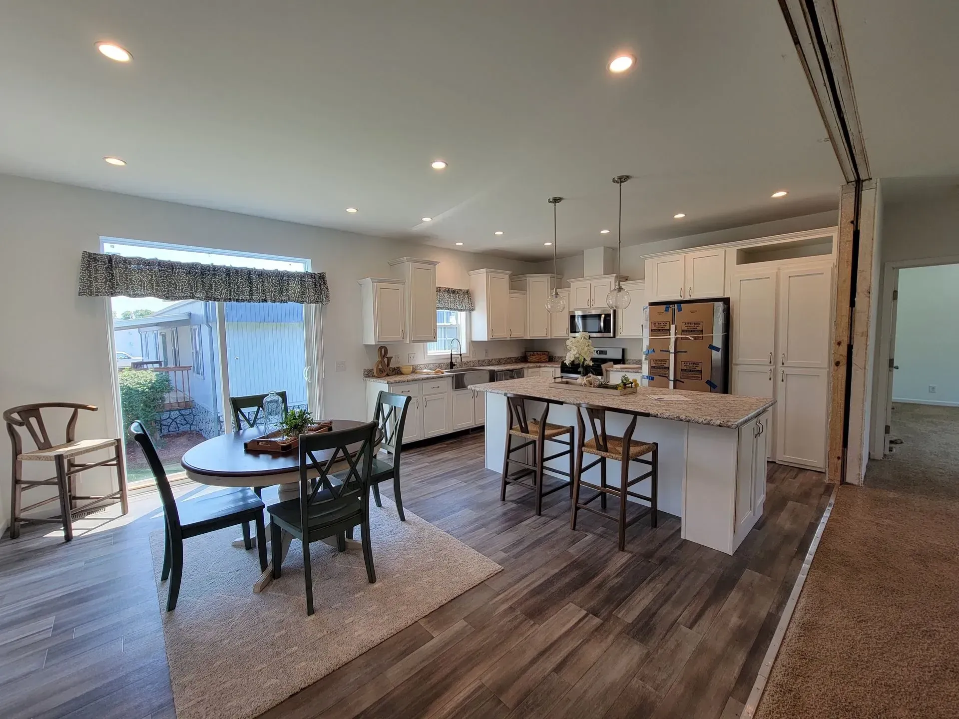 Open-concept kitchen and dining area with white cabinets, island, and dining table; hardwood-style floors.