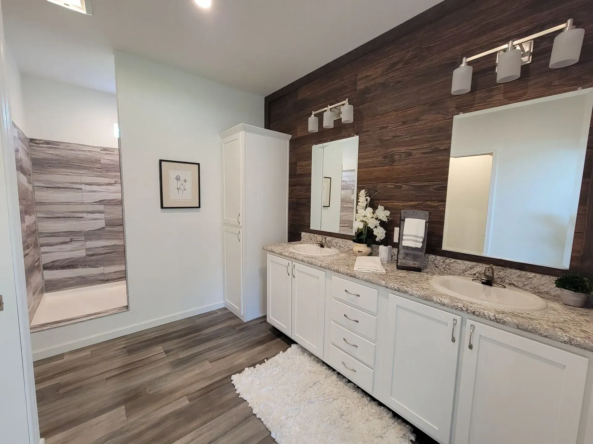 Bathroom with white cabinets, wood accent wall, and walk-in shower.